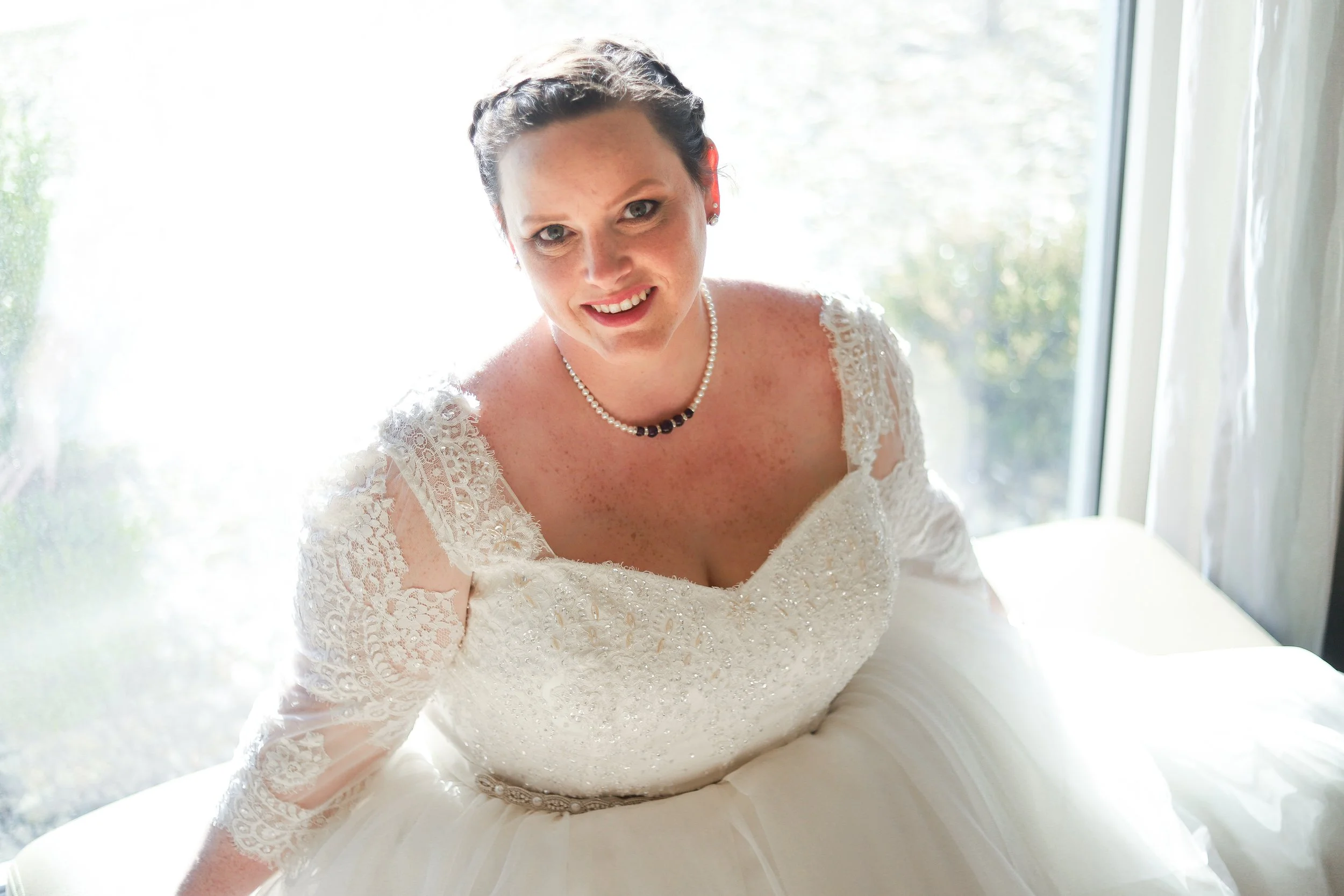 A woman in a wedding dress with a memorial necklace from her grandma's funeral flowers.