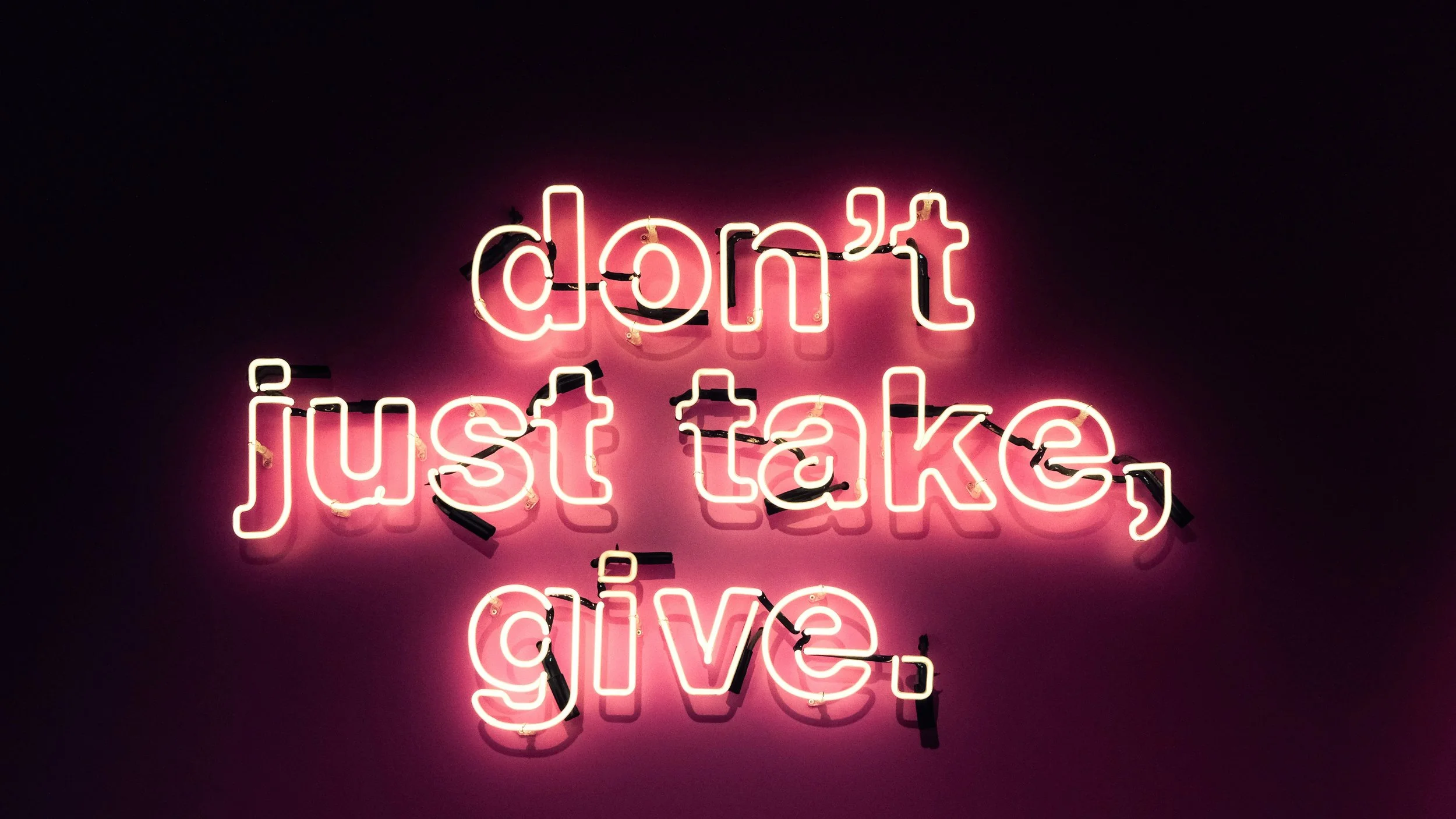 Neon sign reads, don't just take, give