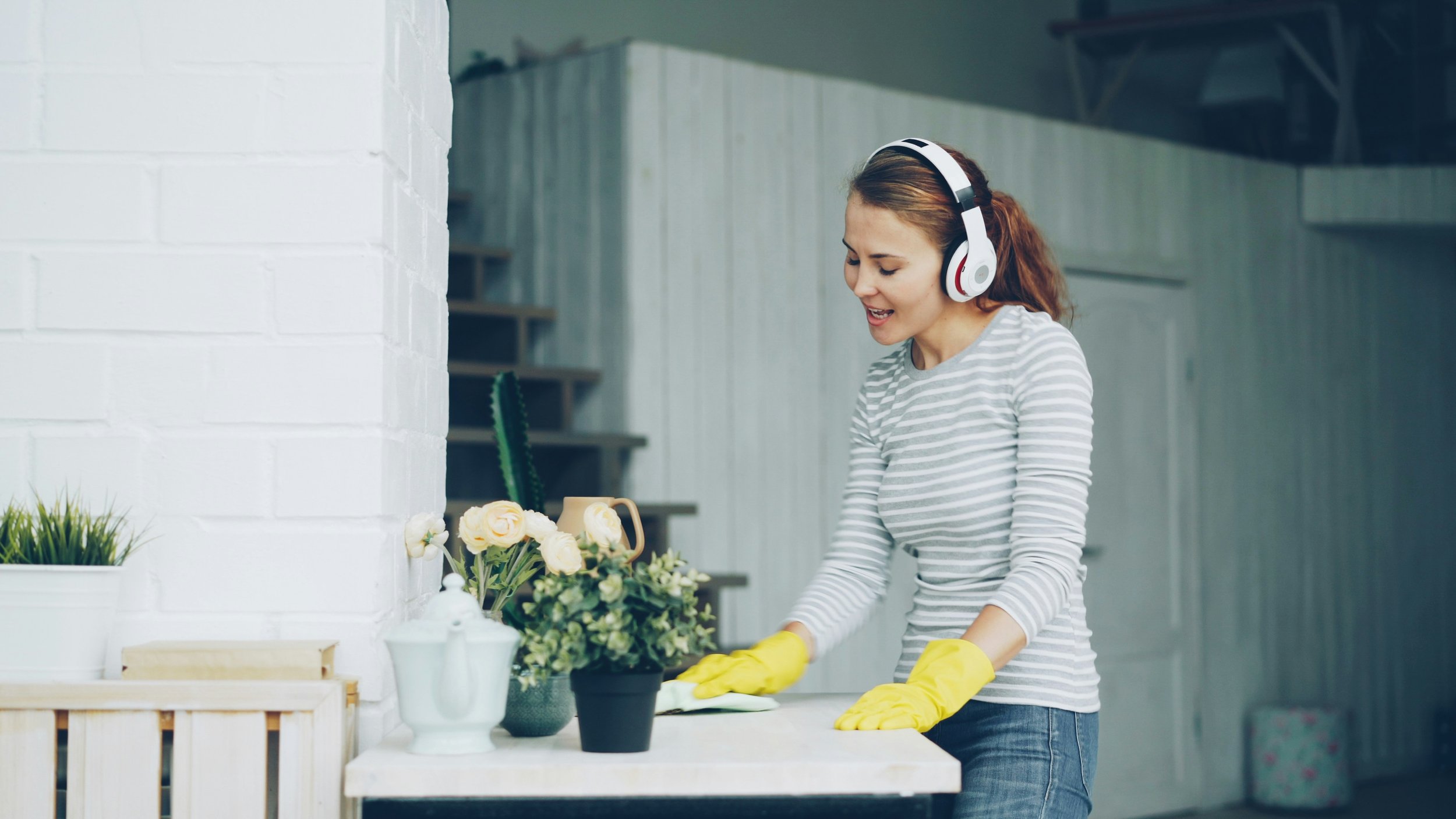 Woman cleaning counters while wearing headphones and singing