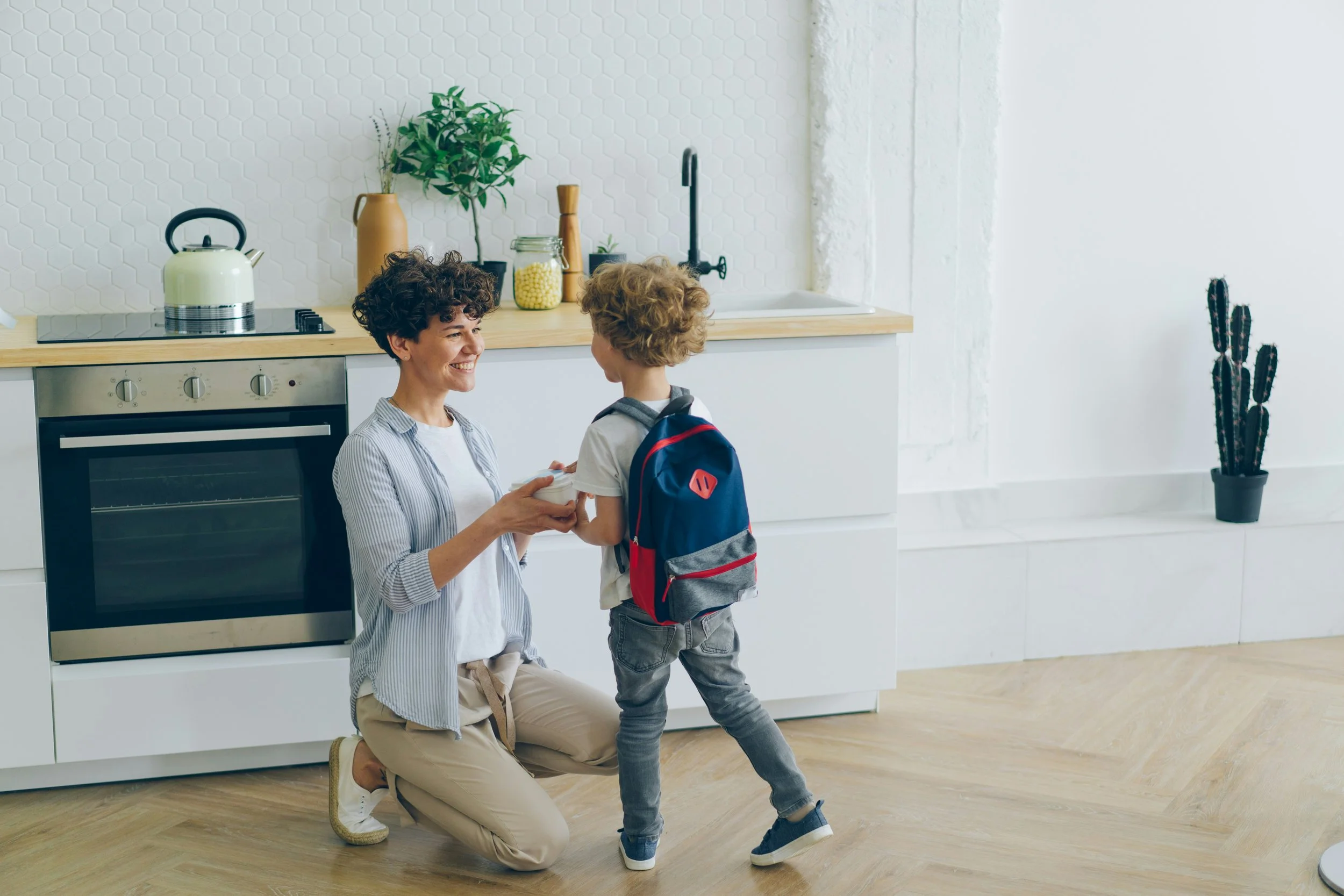 Mother greeting child wearing backpack