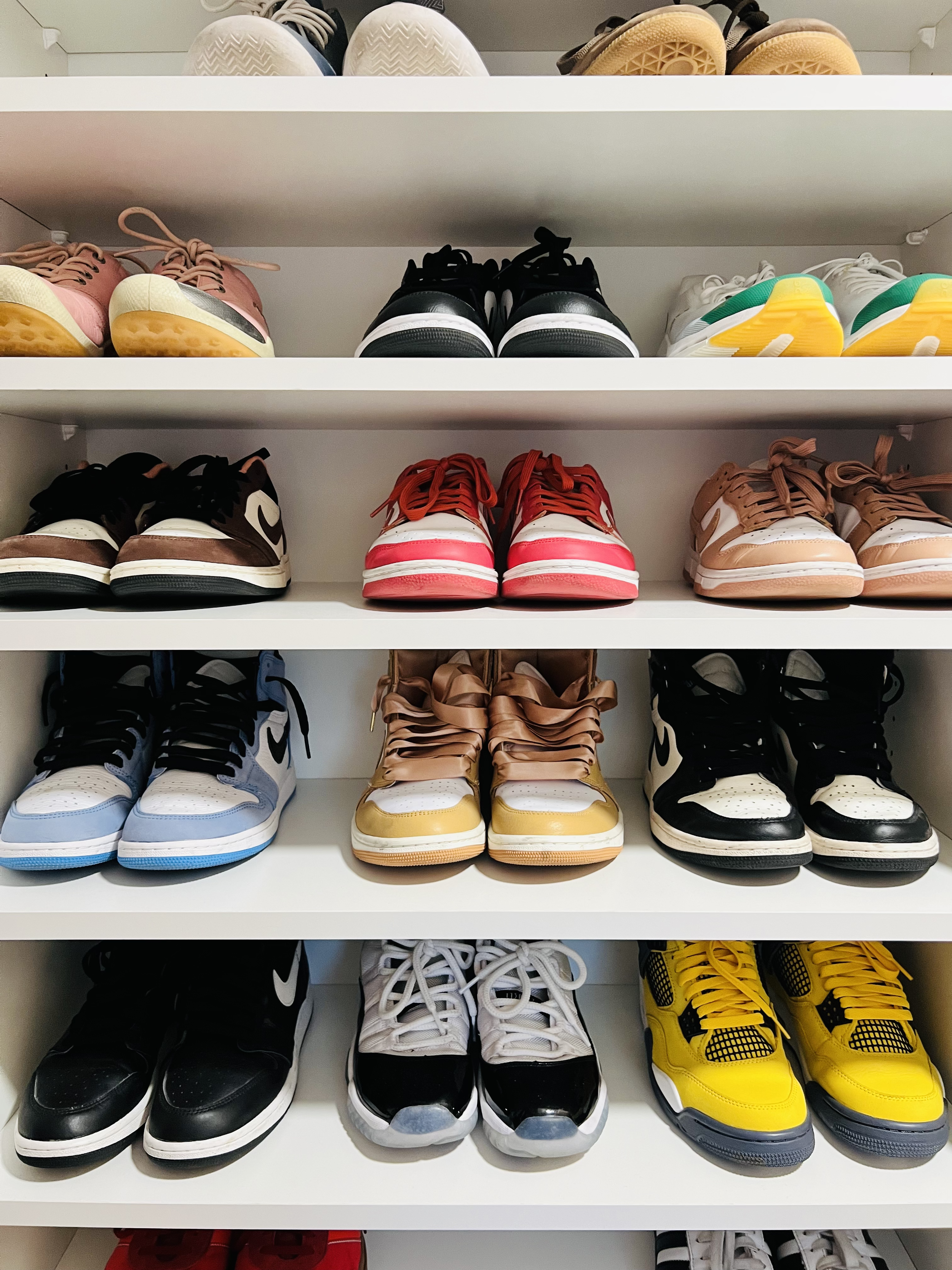 Sneakers on a white shelf in a shared closet