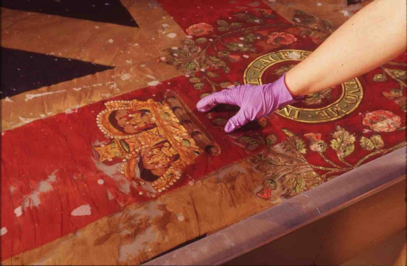 Conservator wearing protective gloves working on a historic embroidered panel from Linlithgow Museum’s collection.
