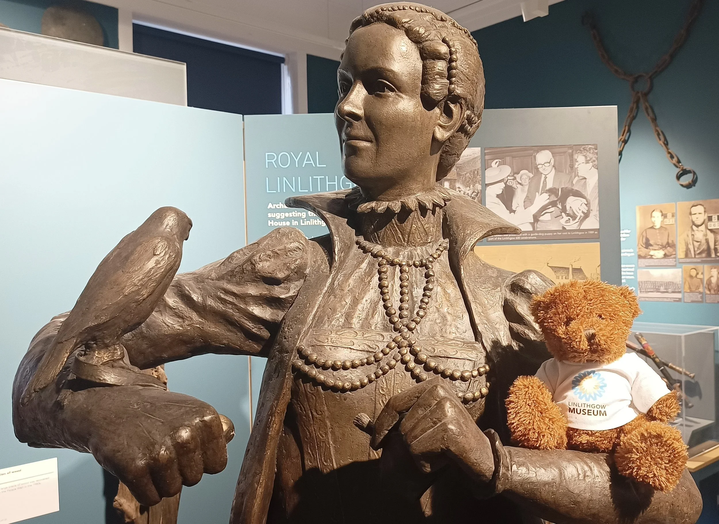 Statue of Mary, Queen of Scots holding a Linlithgow Museum teddy bear in the museum gallery.