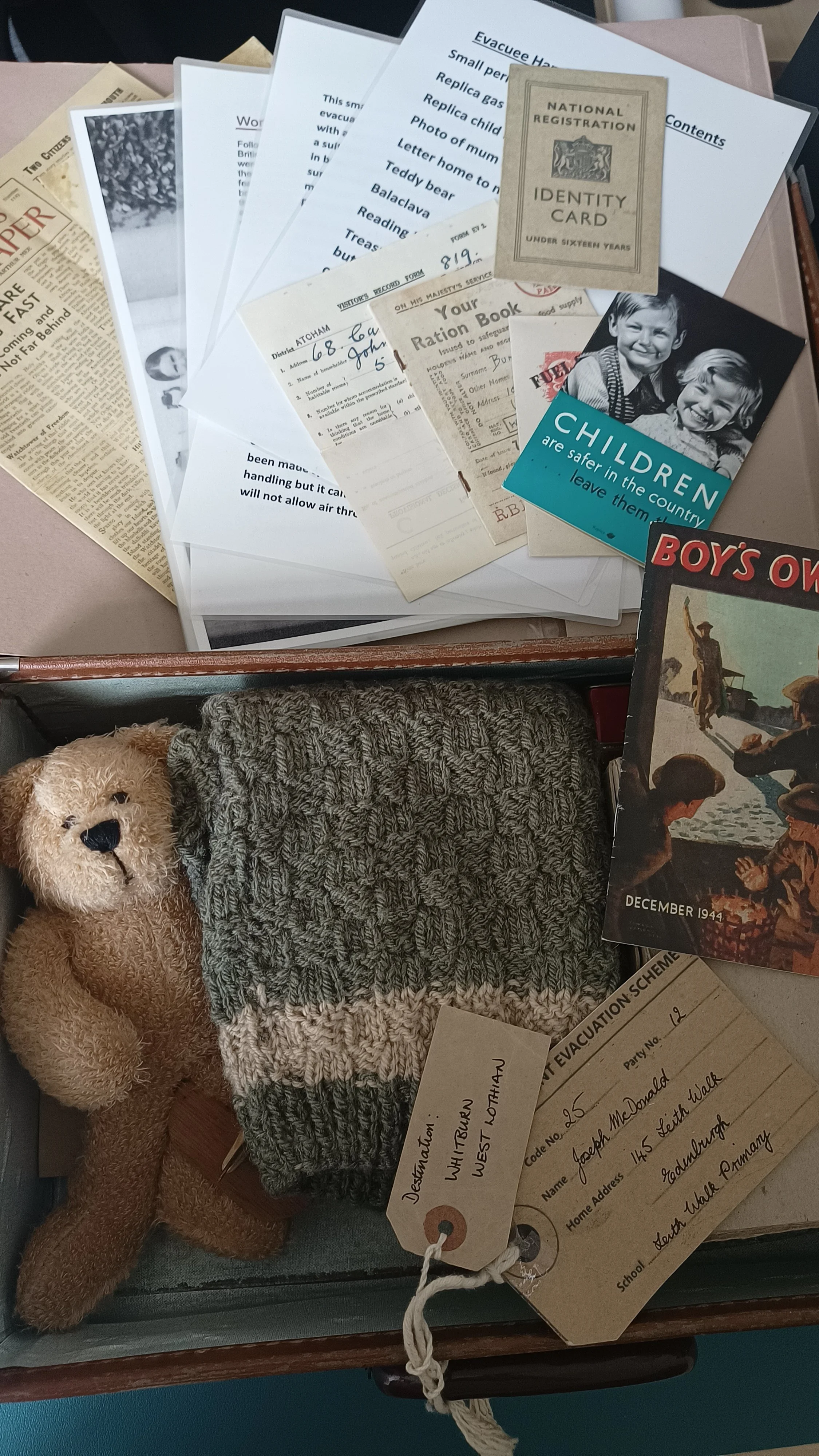 WWII evacuee object-handling suitcase containing a teddy bear, knitted clothing, documents and wartime materials.