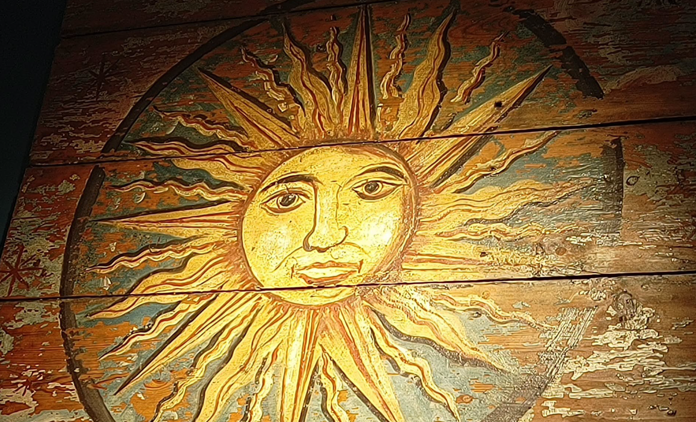 Painted wooden ceiling panel depicting a golden sun with a human face at Linlithgow Museum.