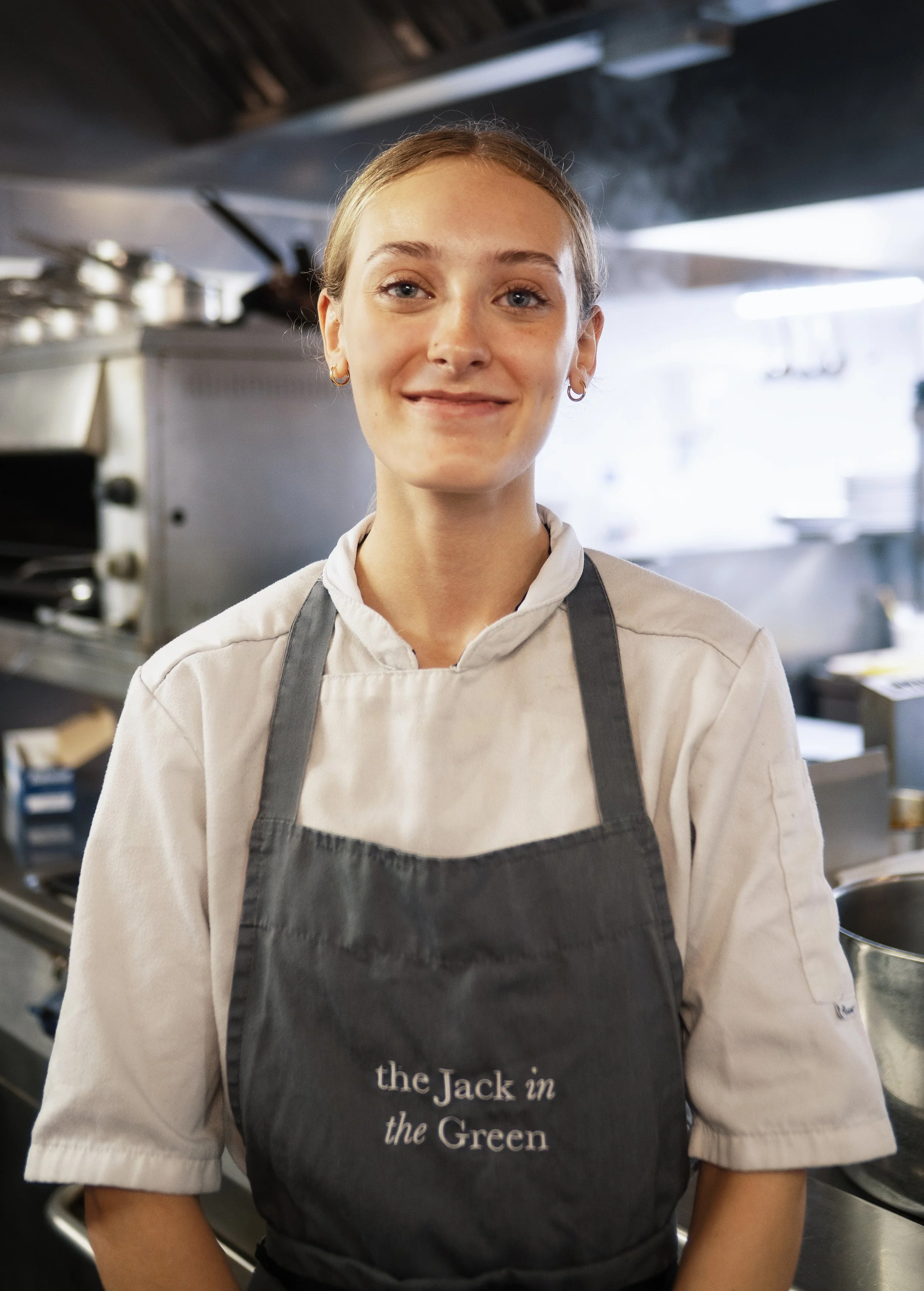A smiling female chef standing in a professional kitchen.