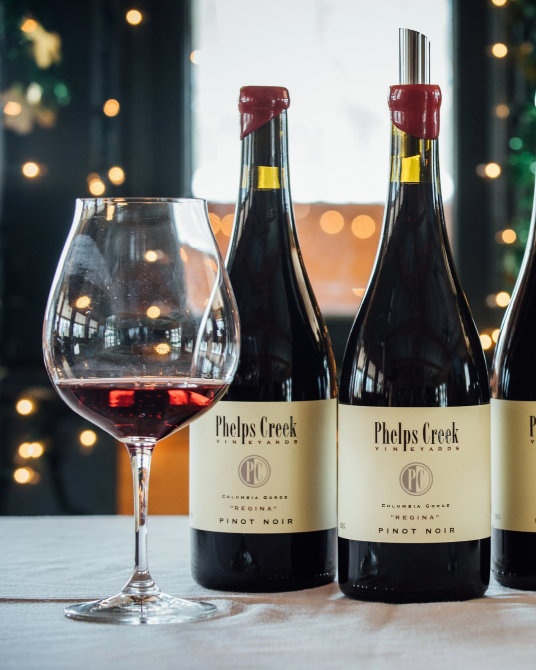 Bottles of Regina Pinot Noir with a glass poured