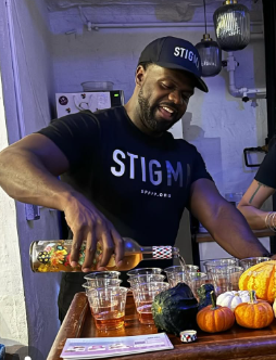 Courtney Brame Founder of  stigma neutralization organization, something positive for positive people in a stigma t shirt that is black pouring non-alcoholic drinks celebrating their NYC herpes support event