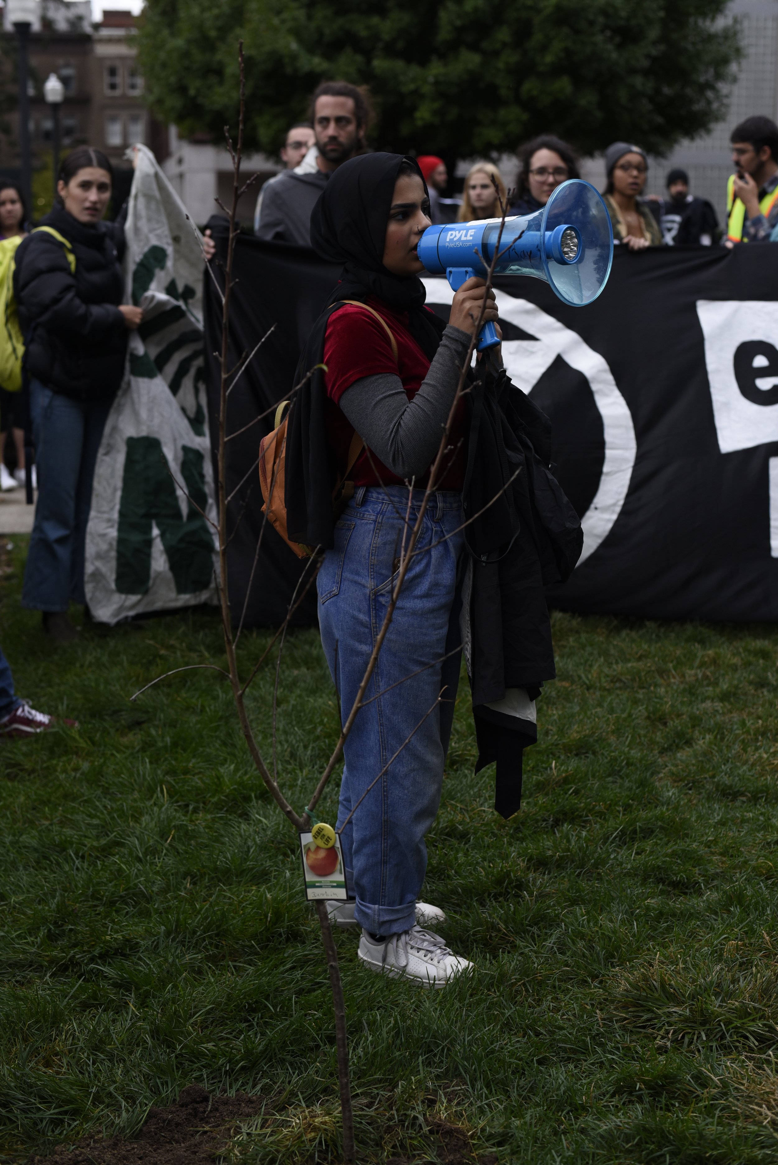  Columbia student speaks through a megaphone  in front of an extinction rebellion banner  