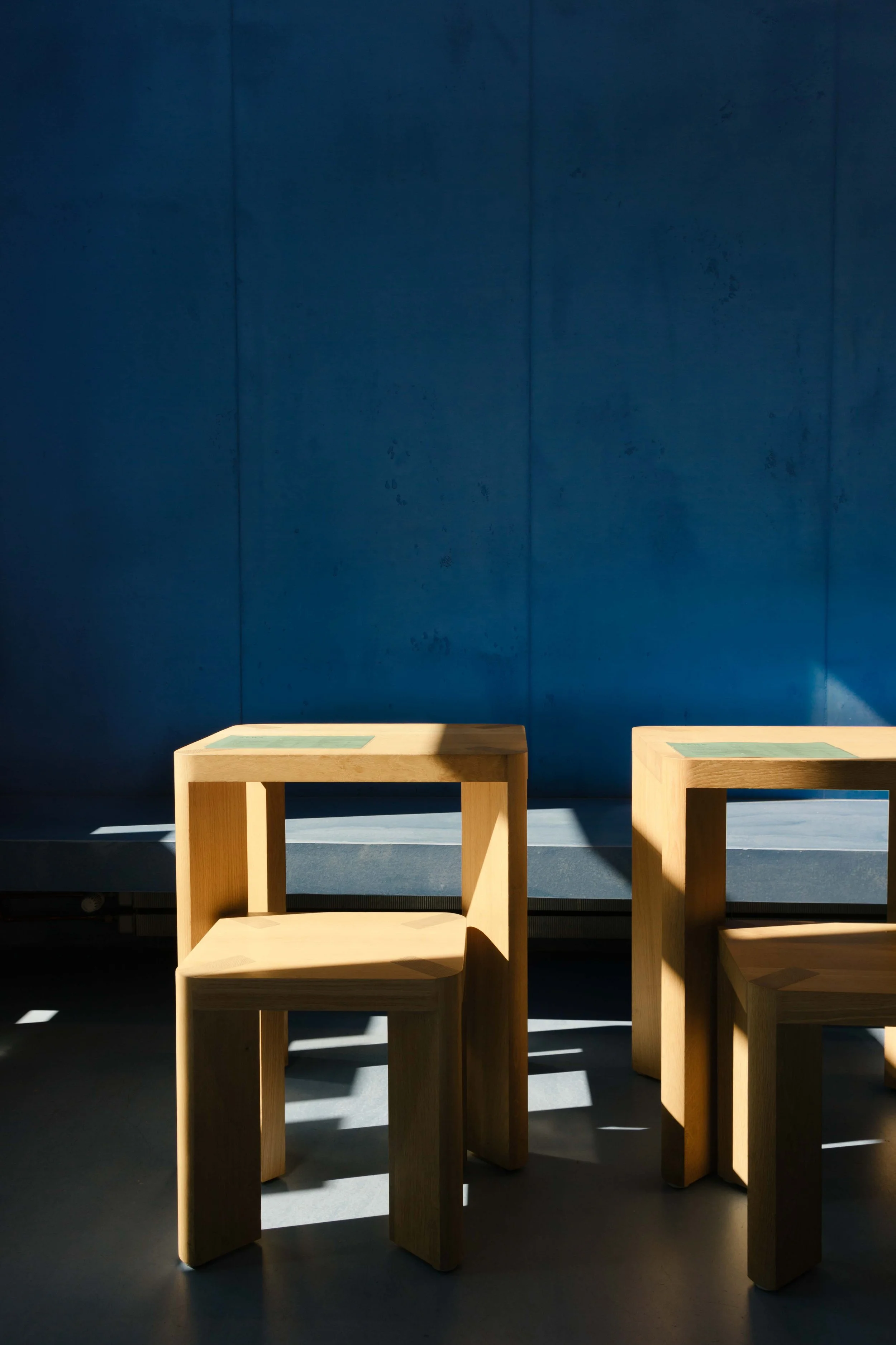 Lapis lazuli blue concrete wall and timber table and stools