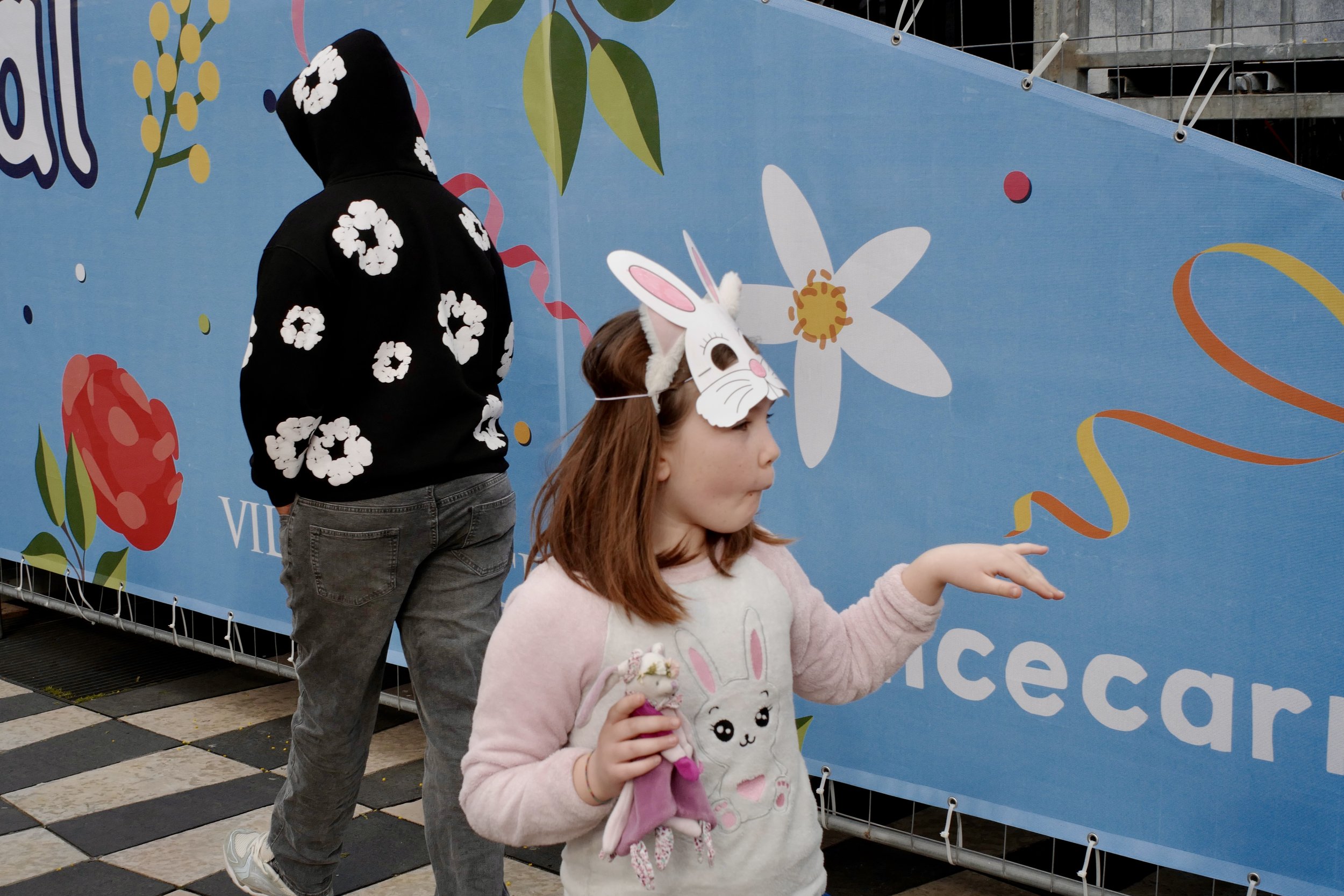 Scène de Carnaval de Nice montrant un chaos organisé entre participants, passants, couleurs vives et proximité humaine