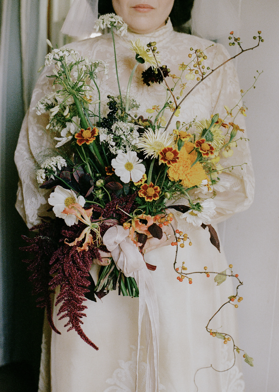 Person in a white dress holding a colorful bouquet of flowers