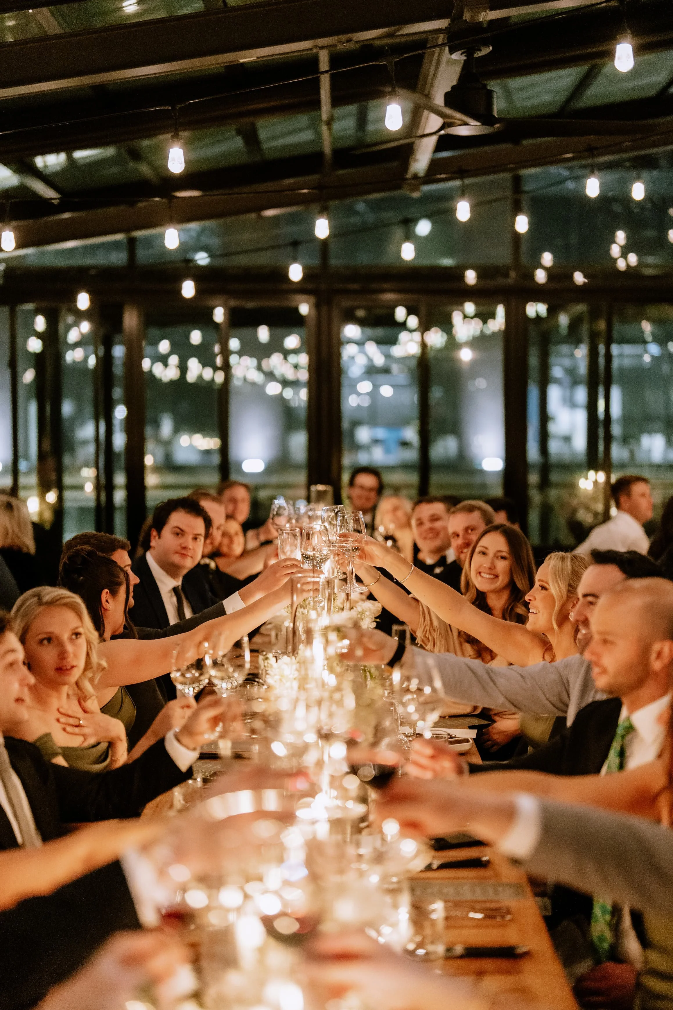 People at a formal dinner party raising champagne glasses in a toast.