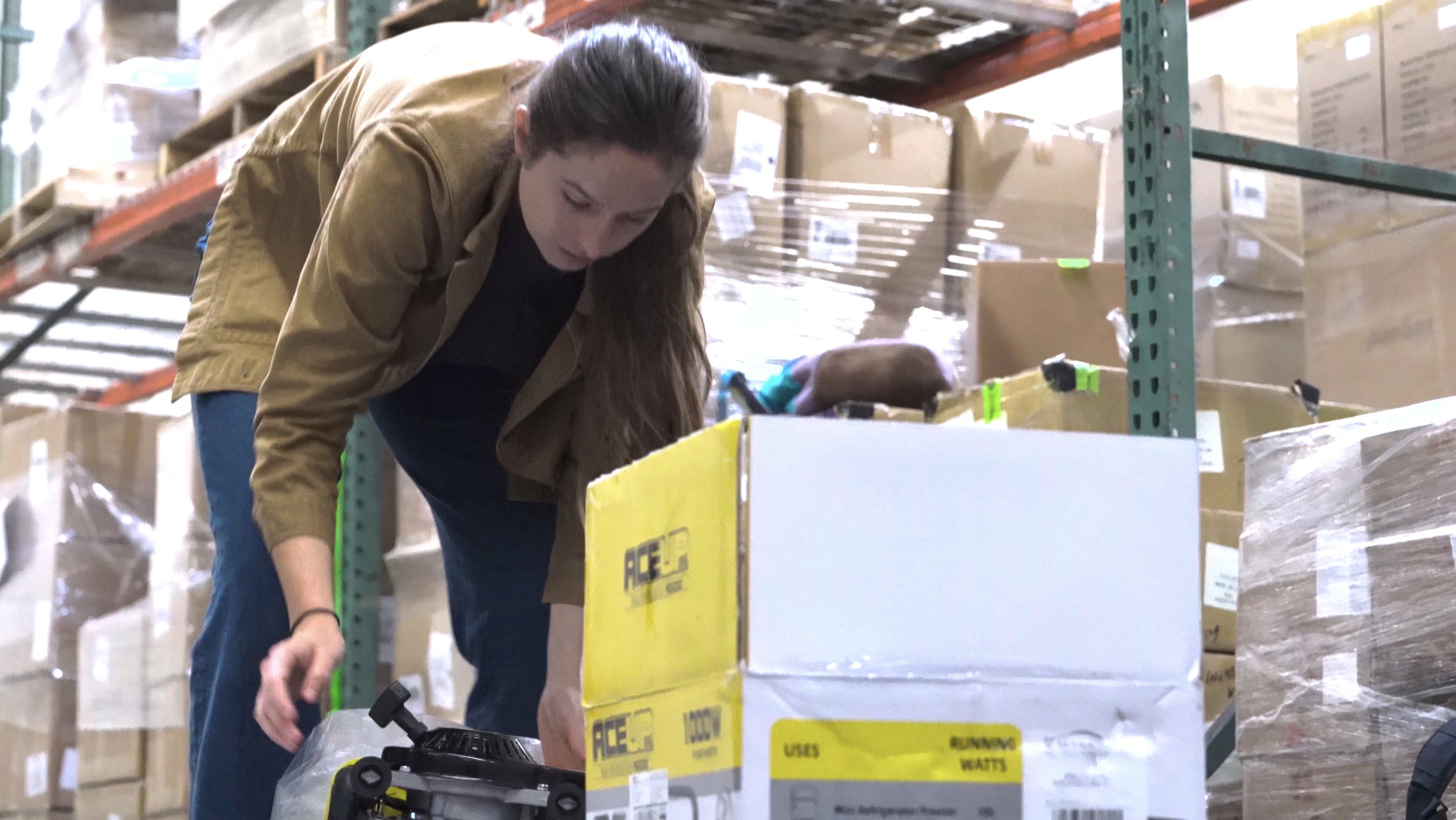 A person inspects a leaf blower in a warehouse.