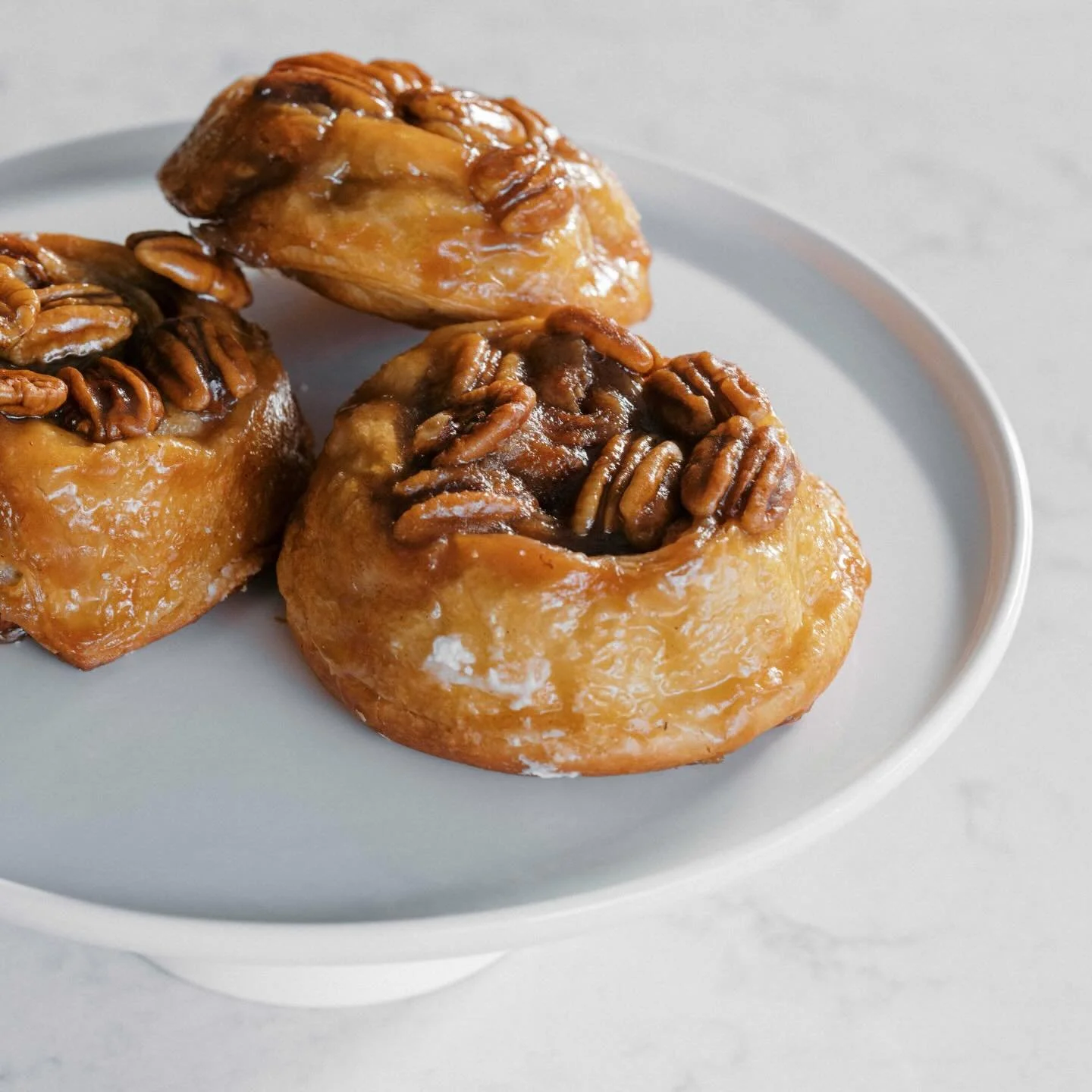 We bake Pecan Caramel Rolls everyday! These decadent, soft rolls are drenched in a rich buttery caramel &amp; topped with crunchy, toasted pecans. 🤎 
#pecancaramelrolls #bakedfreshdaily #breadandchocolatemn #grandavenuesaintpaul
