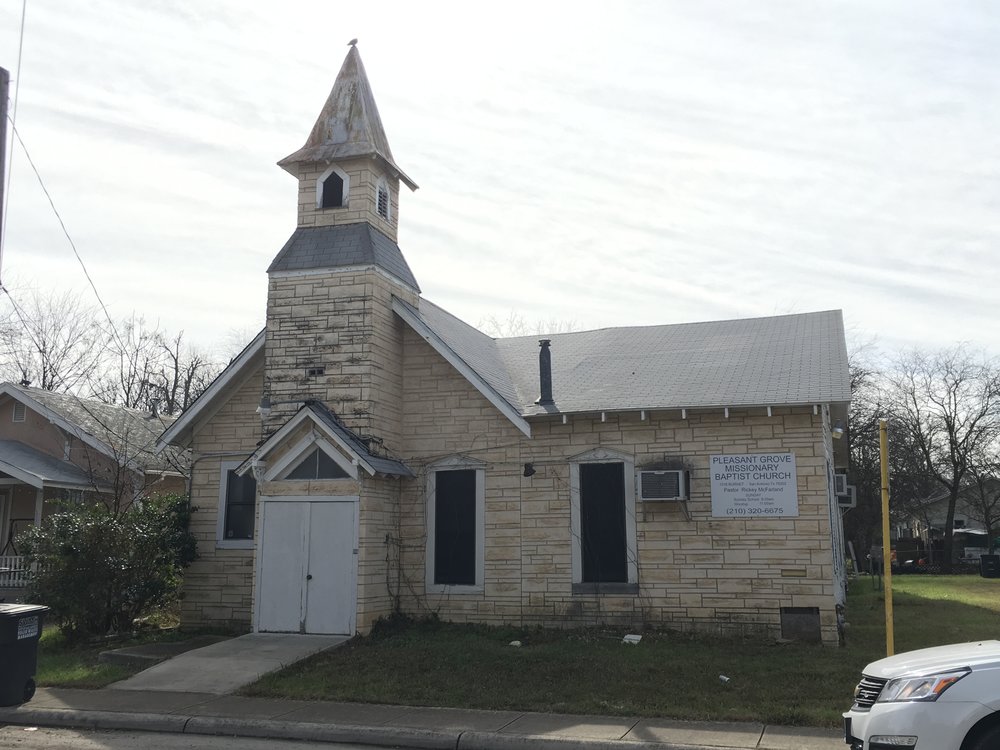  Wooden church with faux stone cladding, a tall steeple with a gabled portico entrance centered beneath. 
