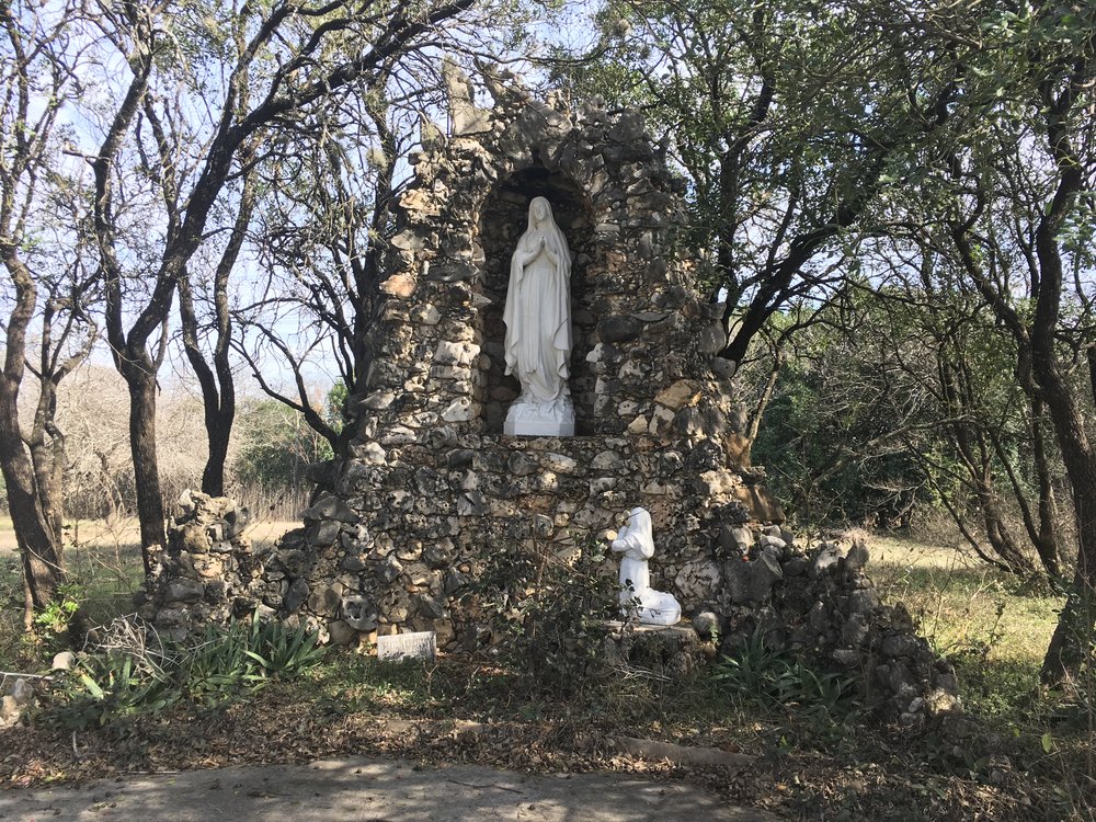  Rough rock grotto with white statue of Mary inside 