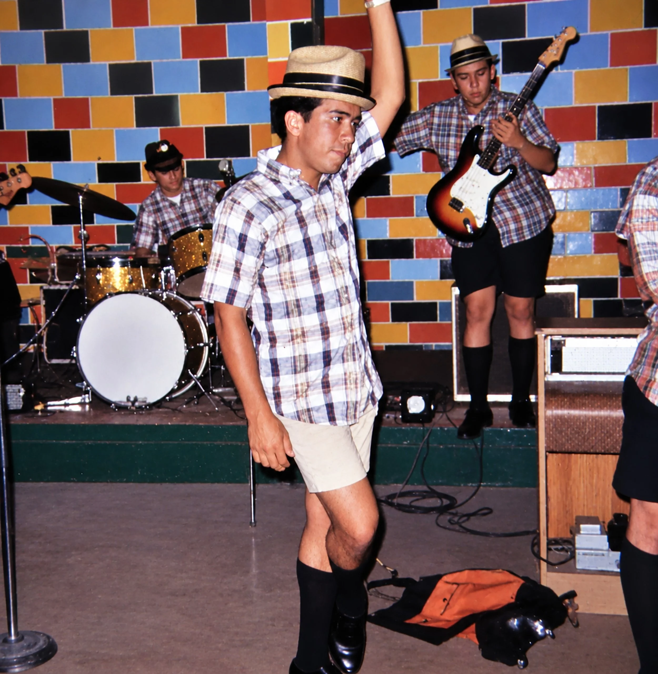 Teenage band, holding different musical instruments are doing a soundcheck, testing their drum, guitar, and bass before a concert.