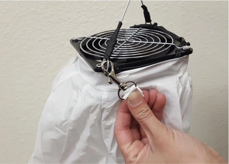 3. Next, clip the 2 metal safety hooks that are attached to the top of the cover onto the cable loops on each side of the fan,