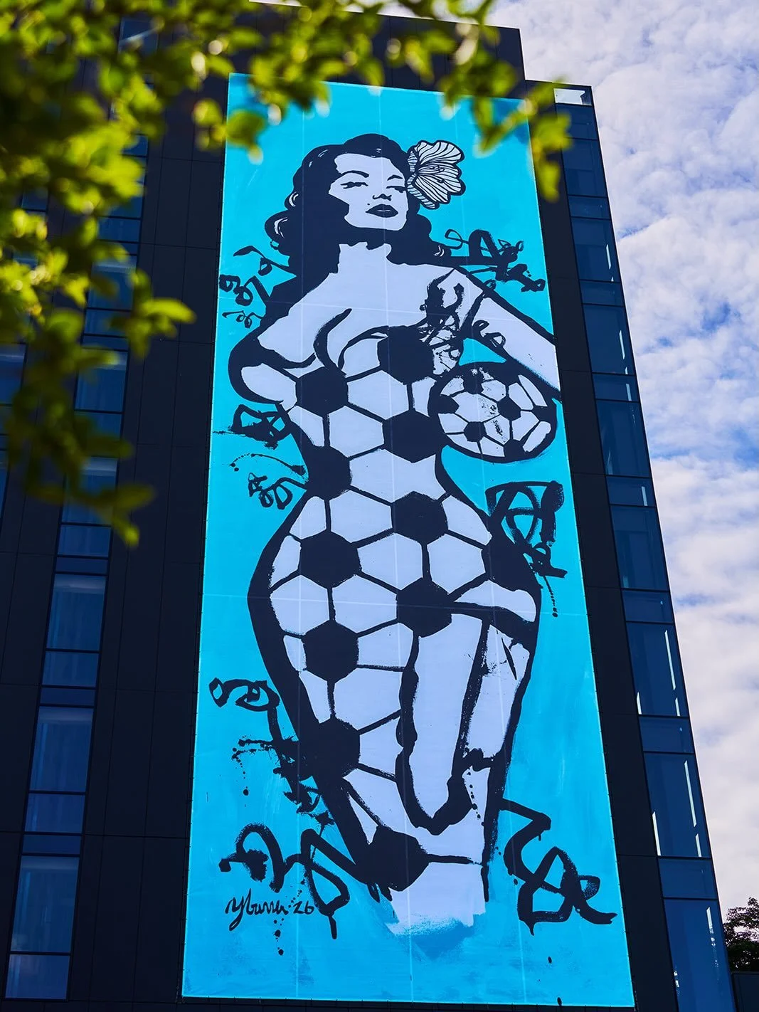 A new 8-story banner installation titled The Hostess, designed by Seattle artist @ernestoybarra, now spans the east fa&ccedil;ade of 9th &amp; Thomas! Commissioned by 9th &amp; Thomas to celebrate the global game coming to Seattle this summer, The Ho