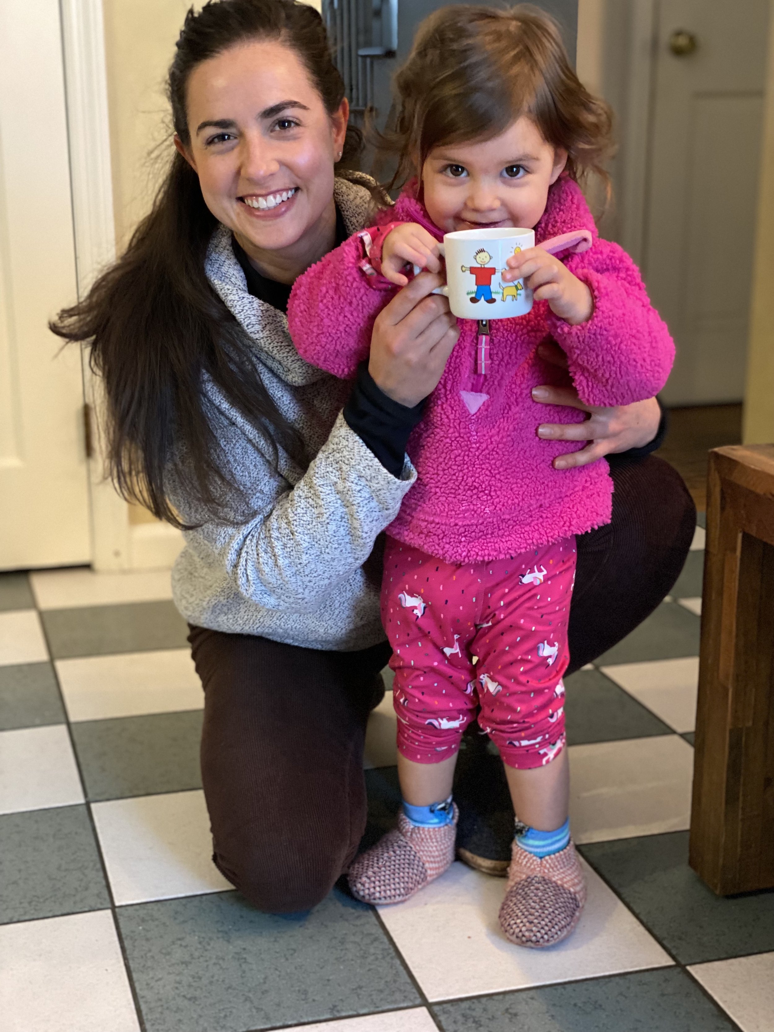 smiling aunt with her 2 year old niece dressed in pink holding a mug
