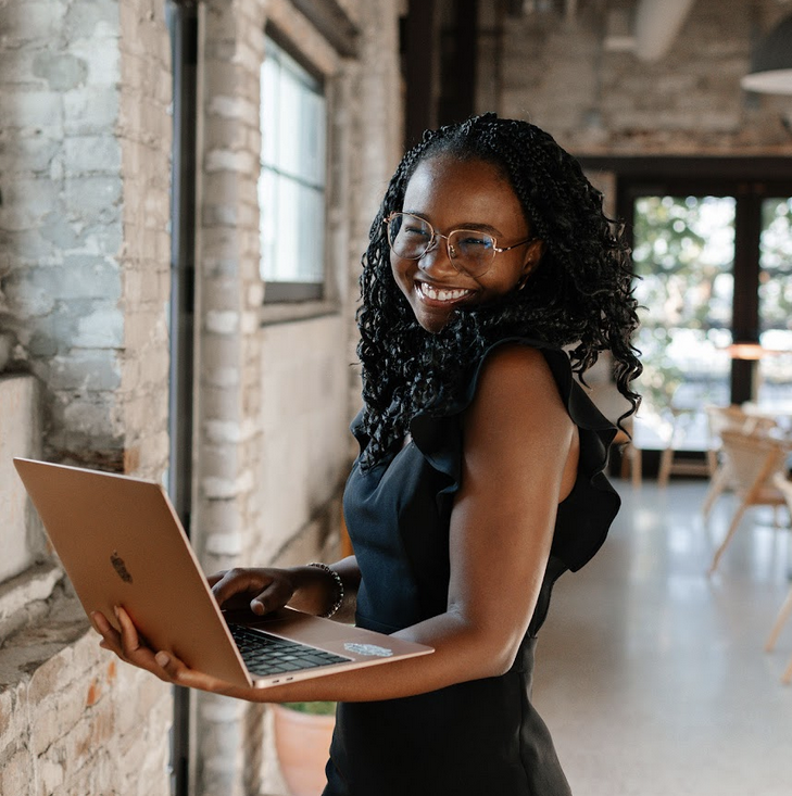Forthright team member Sarah smiles at the camera while holding a laptop