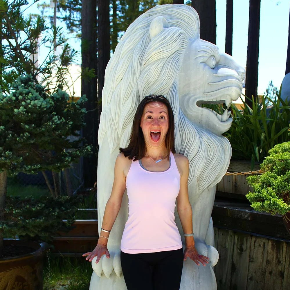 Bernadette making a silly tongue-out stress face while standing next to a lion statue