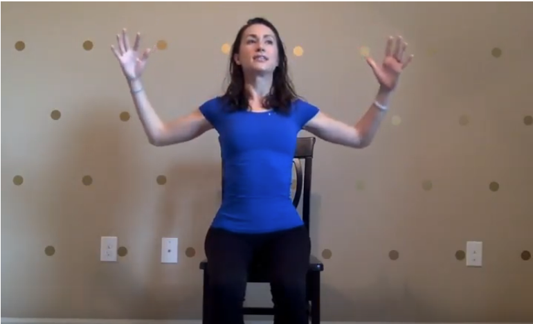 Bernadette demonstrating chest-opening yoga stretch while seated