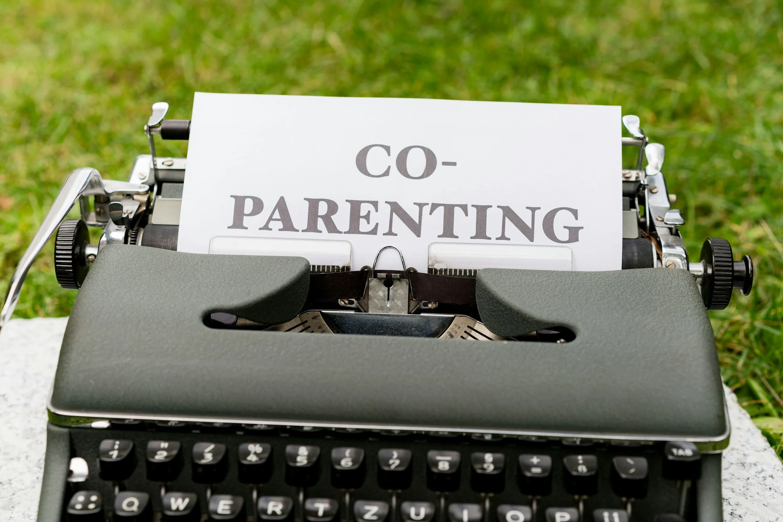 typewriter with paper set in, spelling "co-parenting"