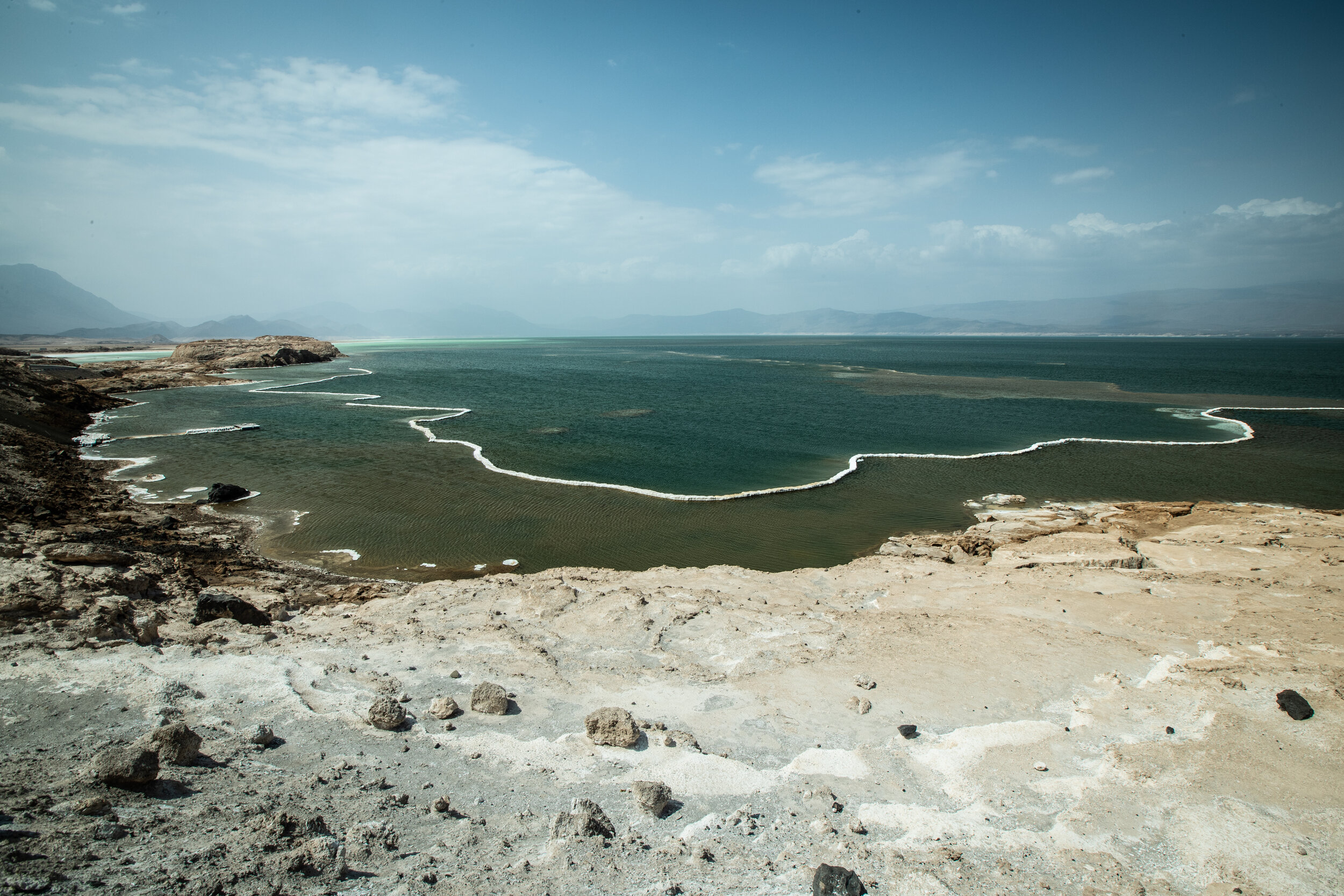  Lac Assal is located in the Danakil Desert and surrounded by dormant volcanoes and black lava fields. this lake is the second lowest point below sea level on earth, after the Dead Sea. the white dry string seen in this picture is a salt bed formed b