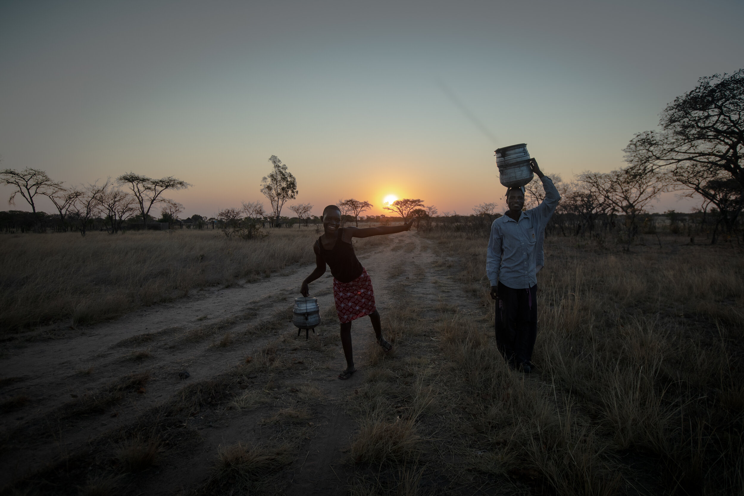  Mediator Mabhunu Matandaurwi and her husband Innocent having fun on their way back home after a walk to sell their artisanal hand made three legged pots, in Chisungo, Zimbabwe, 2019 
