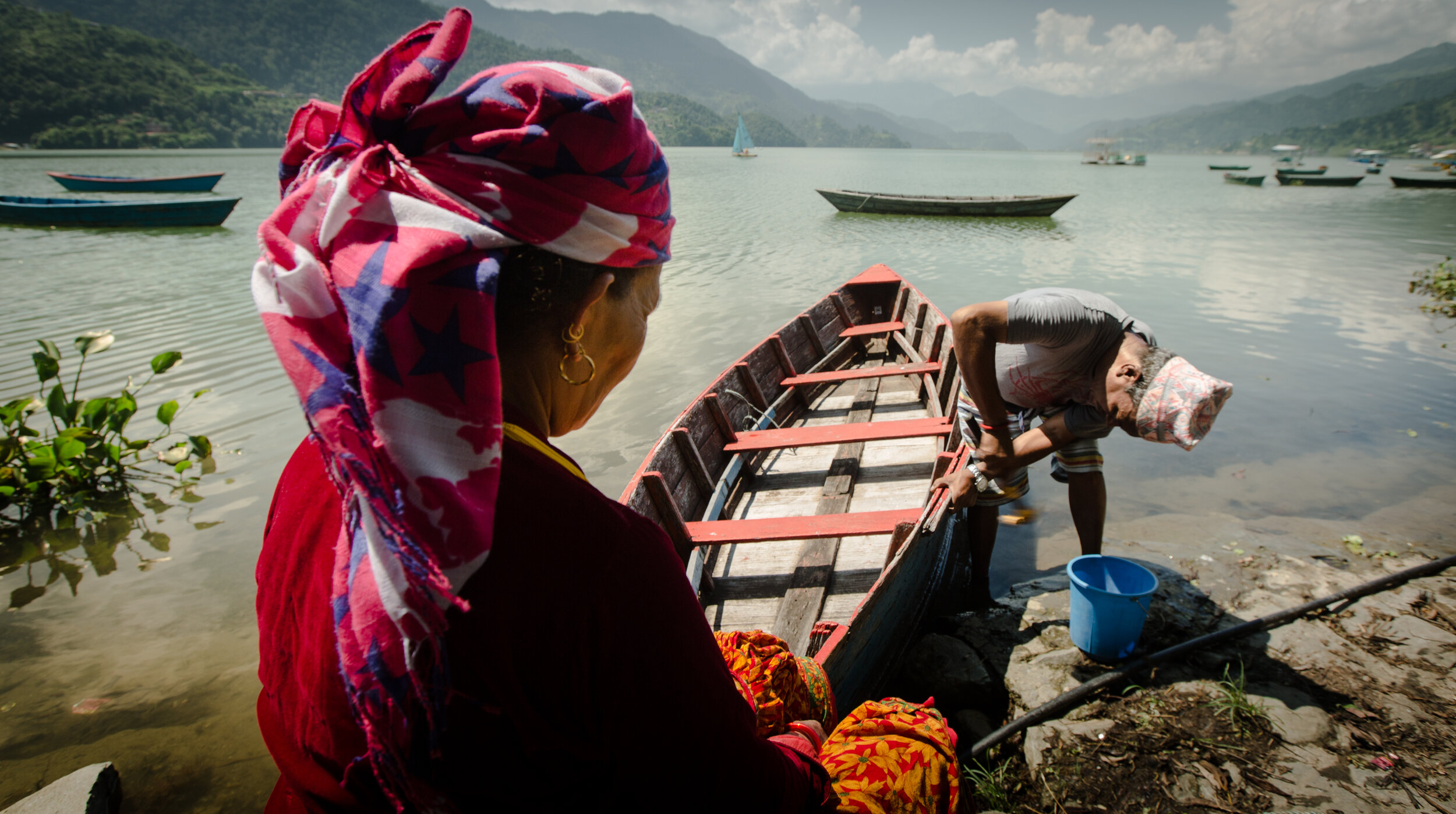  A man fixing a boat and a lady helping him.  2018, Phewa lake, Pokhara, Nepal 