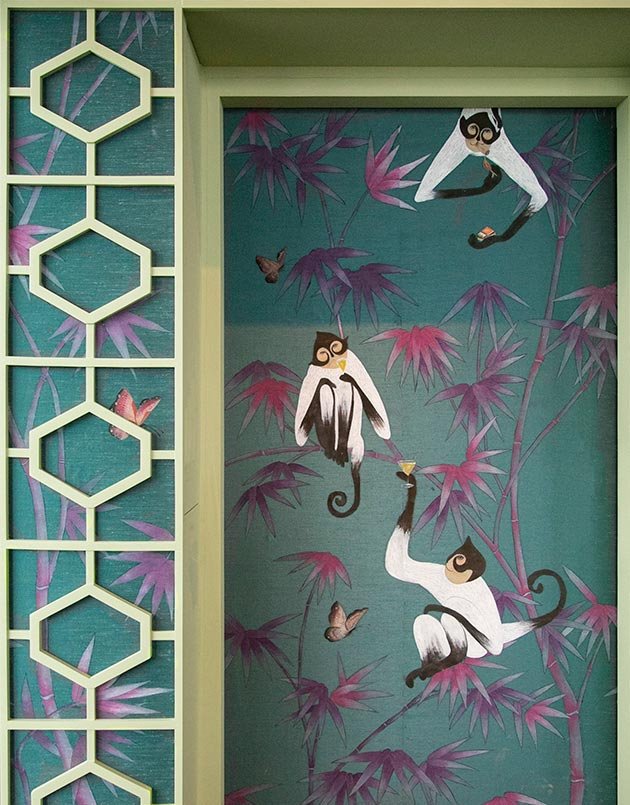  Designer bamboo jungle wallpaper with hand-painted monkeys toasting to joie de vivre, a statement piece for luxury interior designers. 