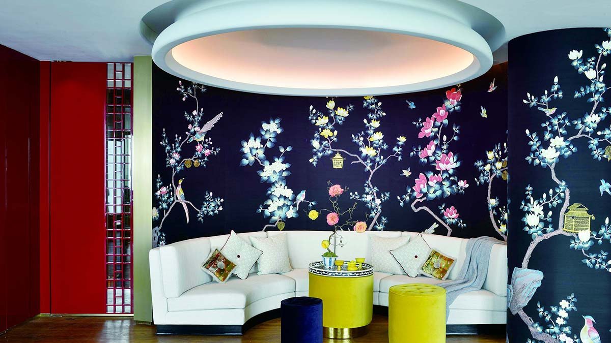  Toro Lanterns Hand-Painted Wallpaper in a living room: A dark floral design with white flowers against a dark wood floor, complementing a luxurious interior with a circular couch and chandelier. 