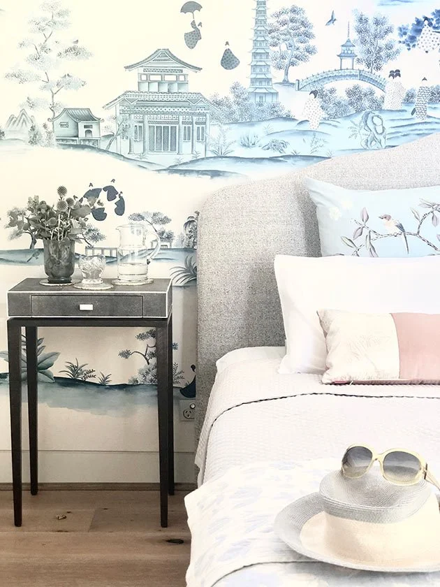  Chinoiserie Village wallpaper enhancing a calm and relaxing bedroom decor with white bed and dark wood nightstand, ideal for sophisticated oriental interior decoration. 