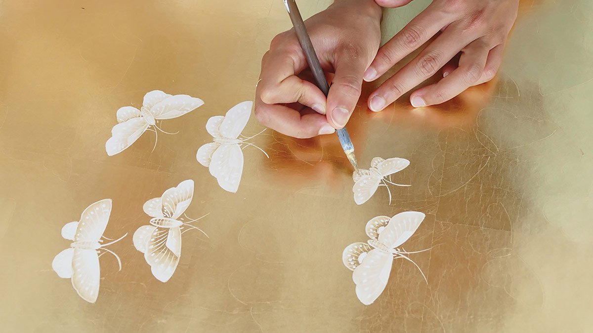  Artistic scene of a woman's hands creating elegant white butterflies on a gold background, romantic and delicate design from Butterflies Retreat wallpaper collection. 