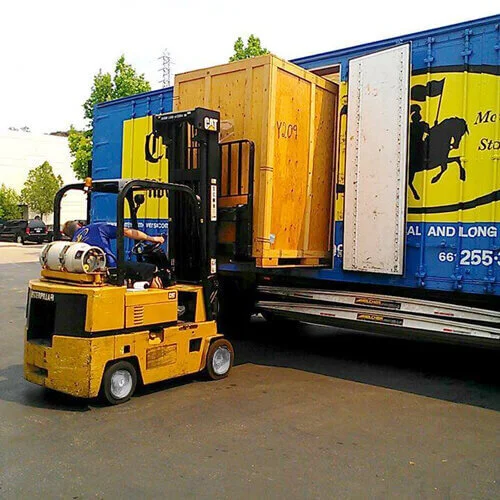 A Camelot employee using a forklift to load a storage unit onto the truck for delivery.