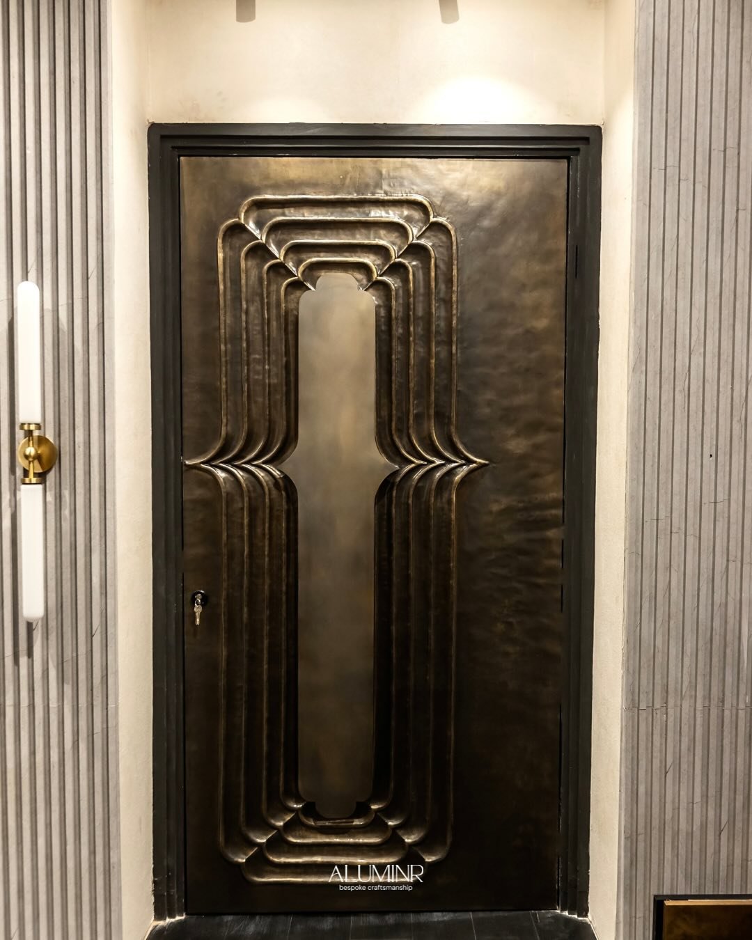 BLOSSOM : part of our 2024 collection and our Regal Repousse collection, handcrafted in bronze, This door is an abstract representation of layers of flower petals. The air element in the form of a floral-shaped handle further adorns the door. Compose