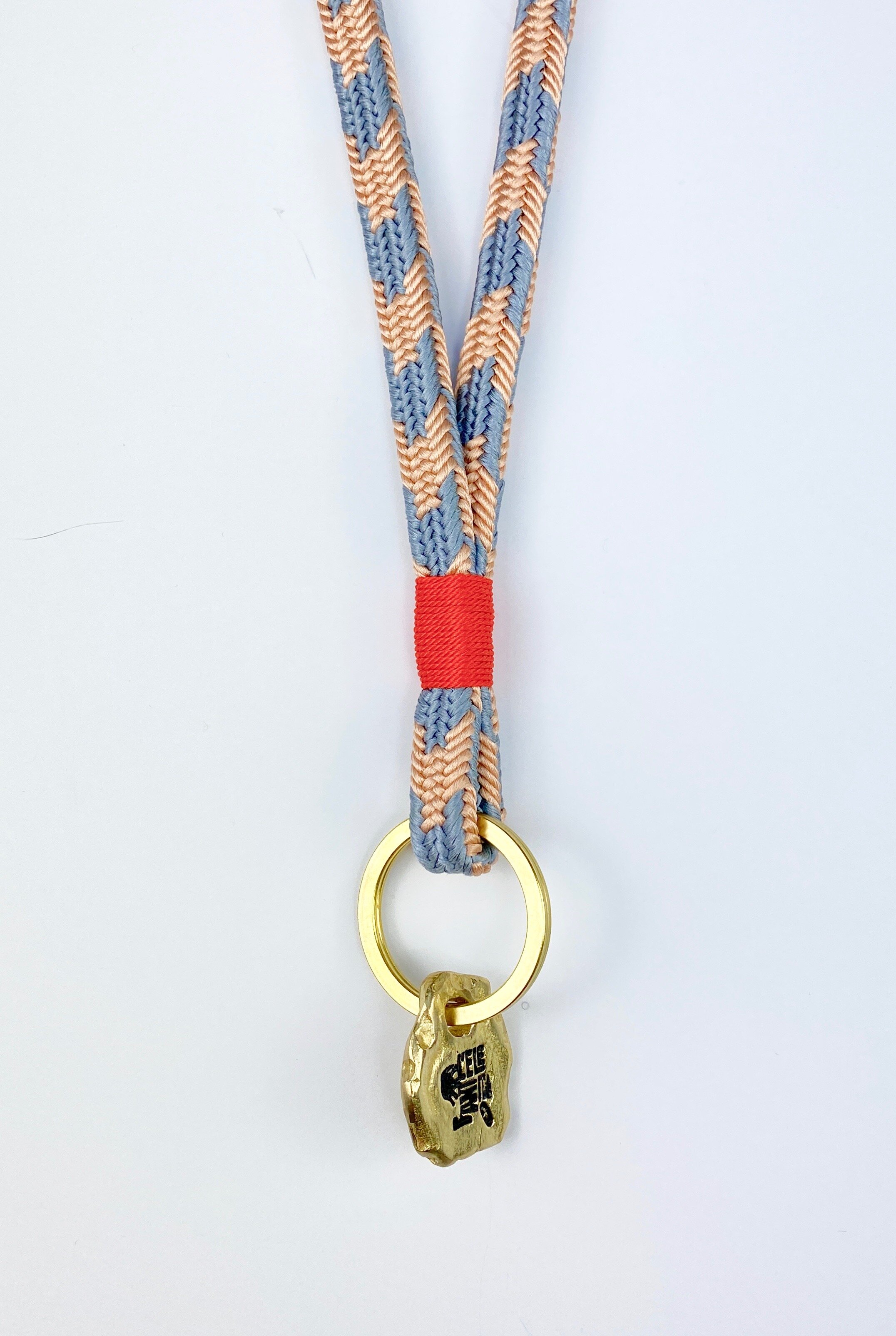 Long Key Strap made out of silk, in the colors baby-blue and cream, with a bright red finish