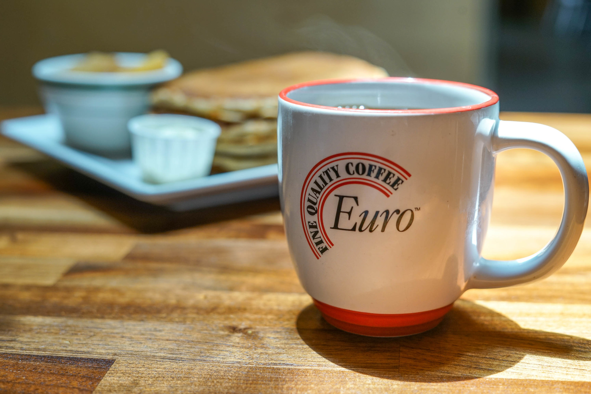  euro coffee cup with pancakes in the background 