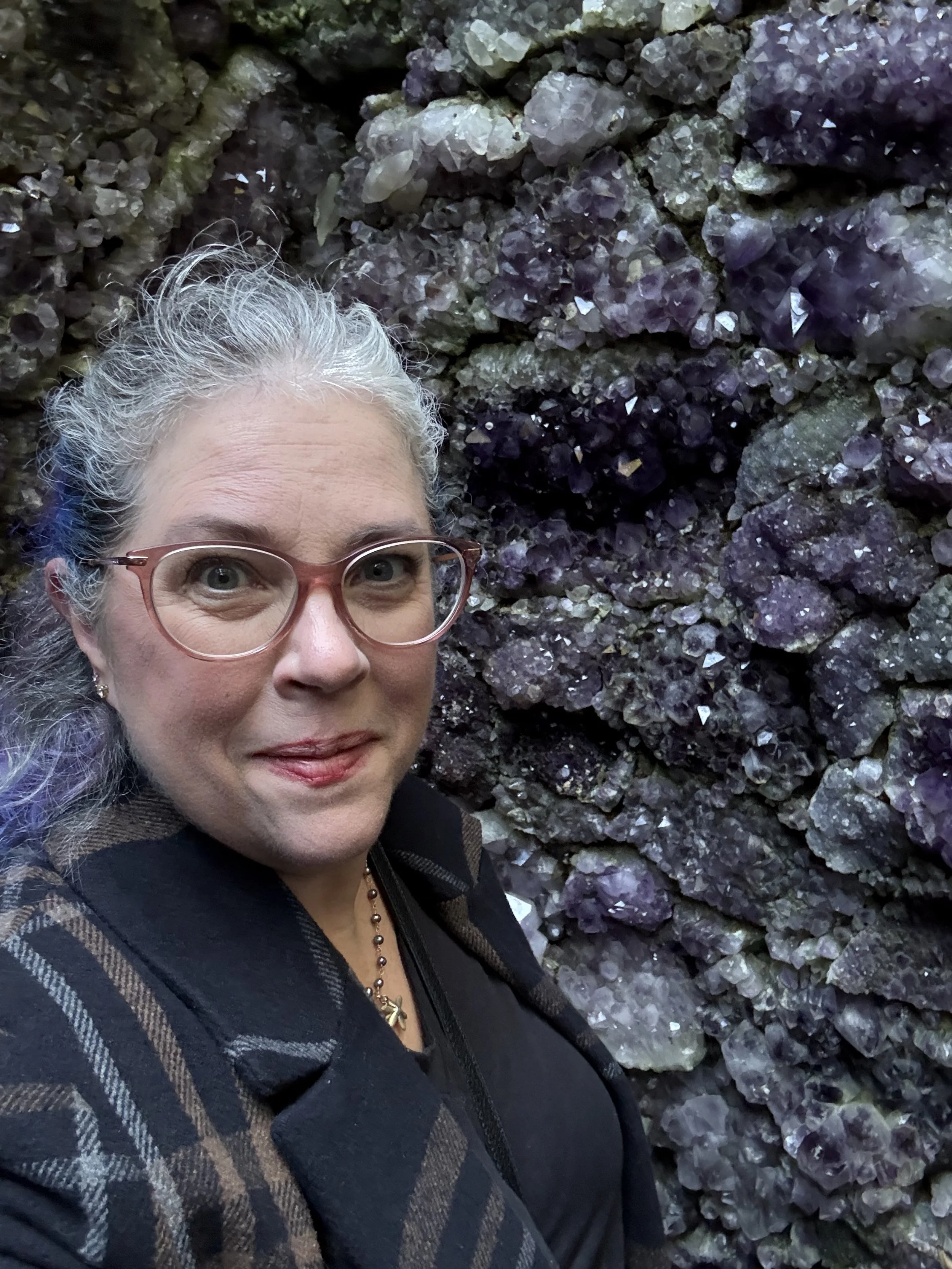 Kelly stands in front of a wall made of amethyst and tourmaline.