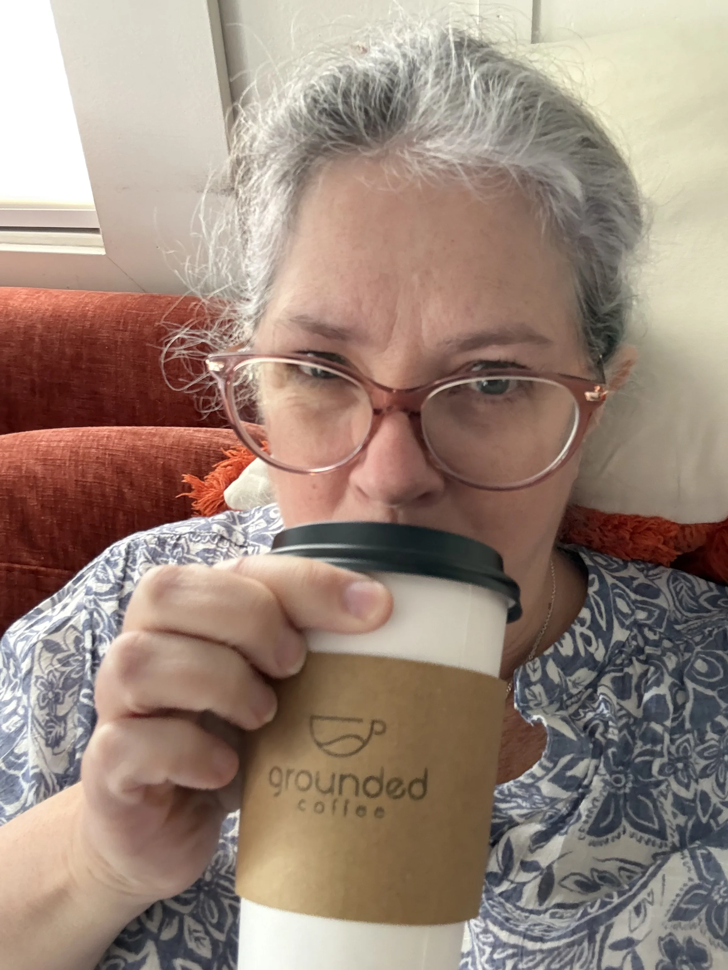 Kelly sips a latte from a to-go cup from Grounded Coffee