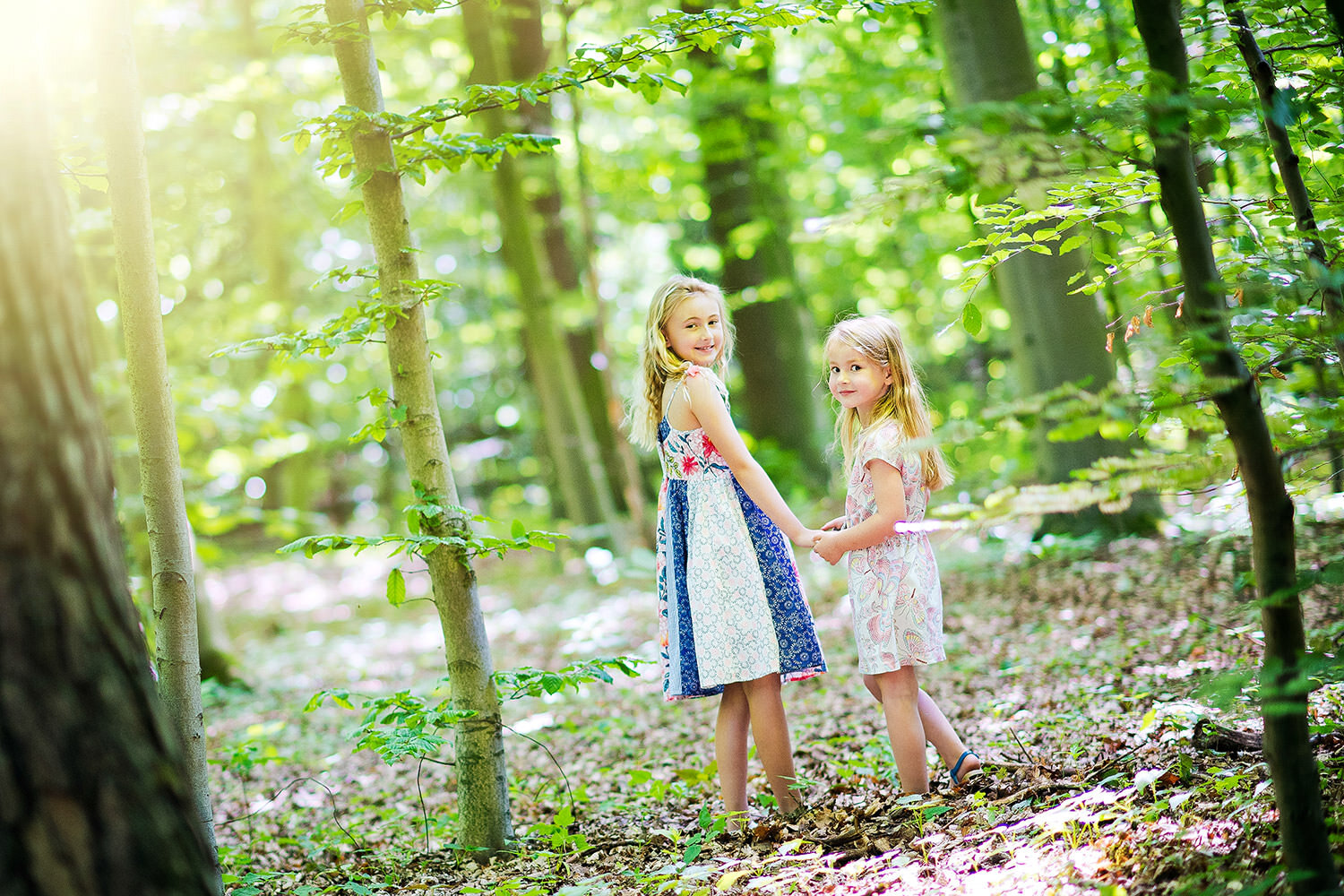 Zwei Mädchen halten sich an der Hand im Wald