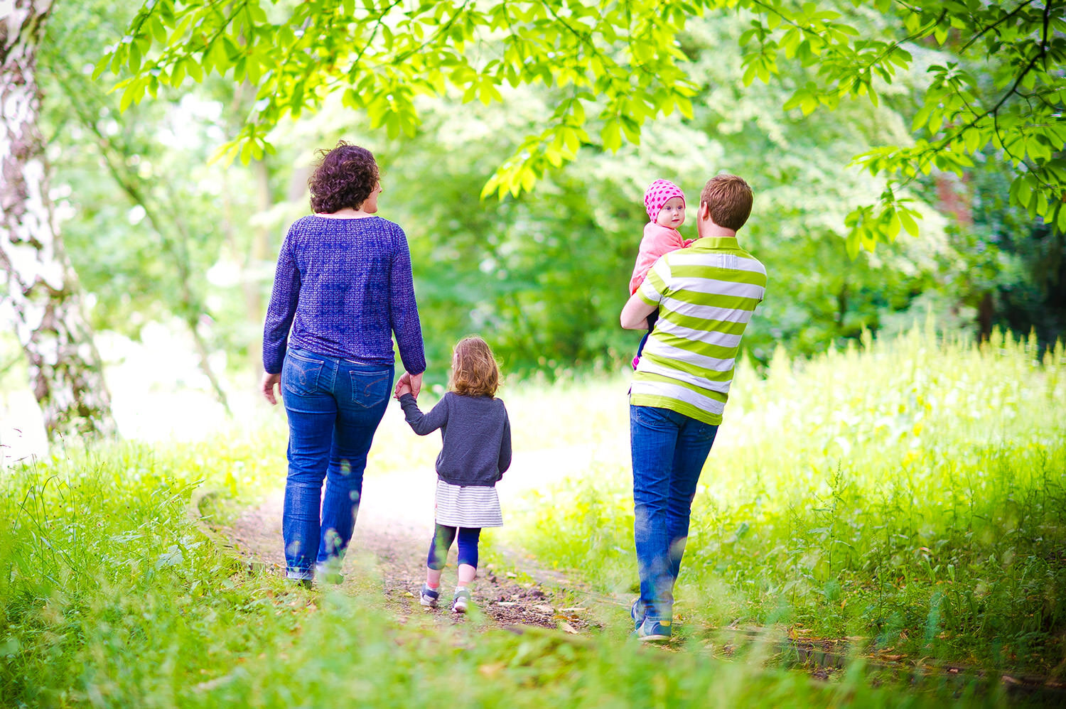 eine junge Familie, die durch einen Wald geht