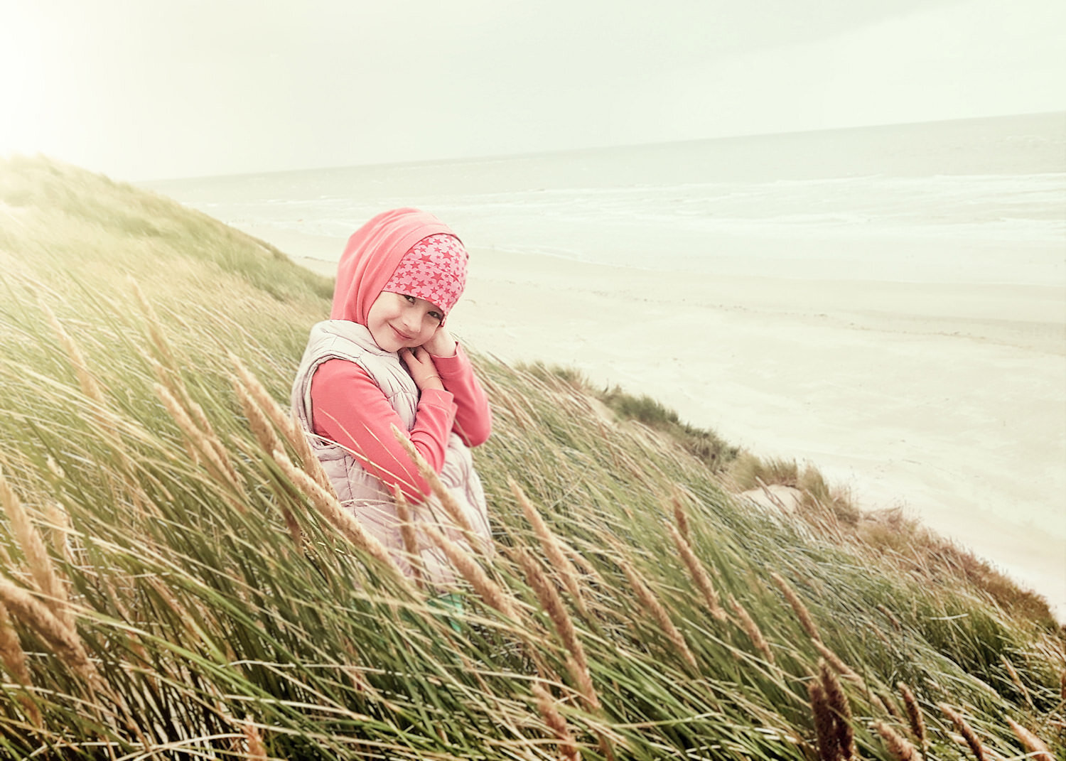 Mädchen in den Sanddünen mit einem rosa Schal