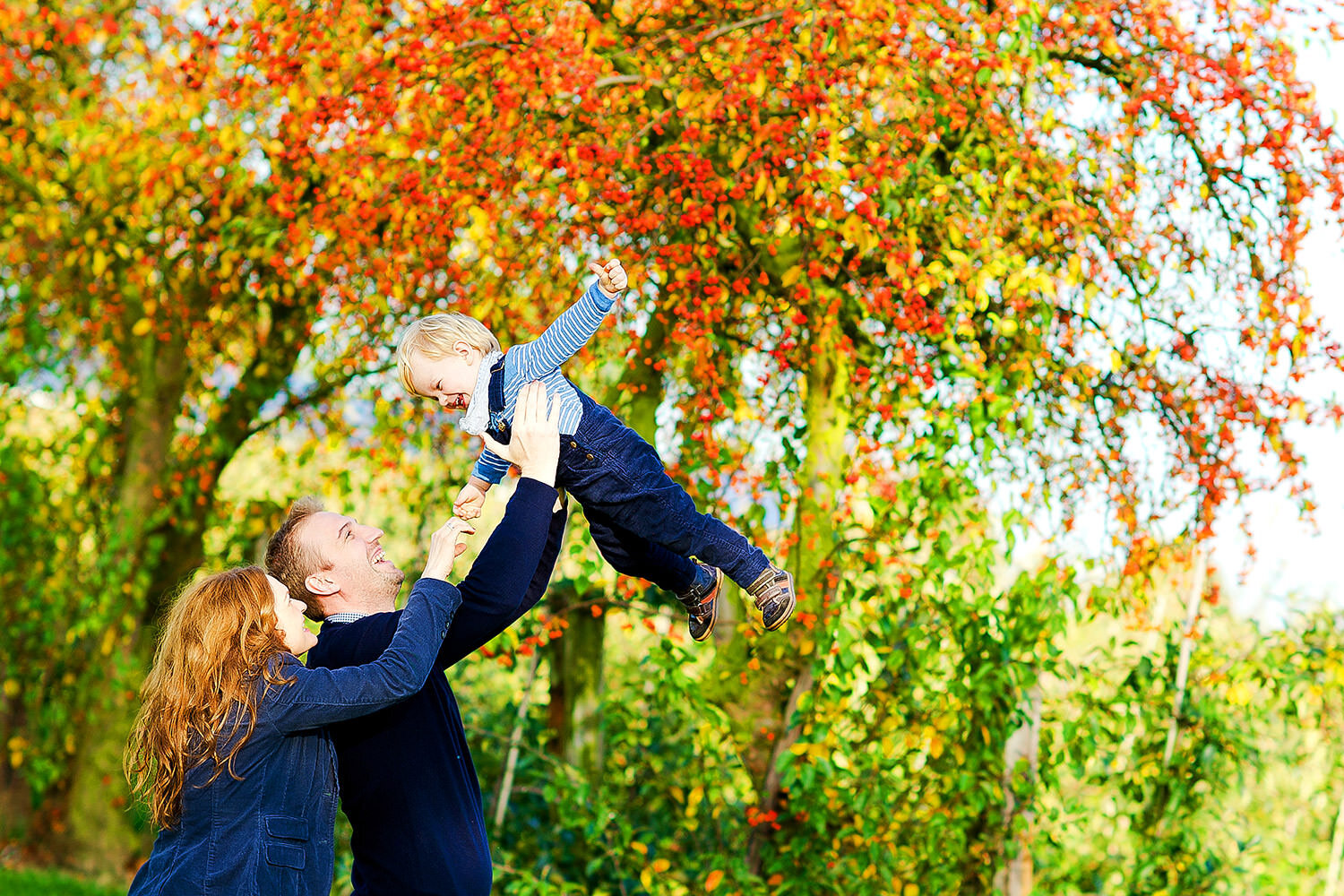 eine junge Familie vor einem Baum im Herbst