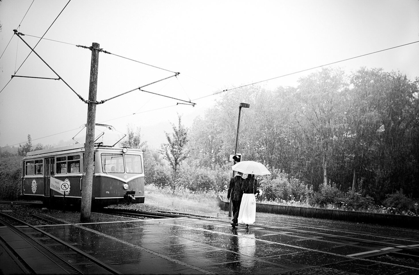 Brautpaar mit Schirm im Regen