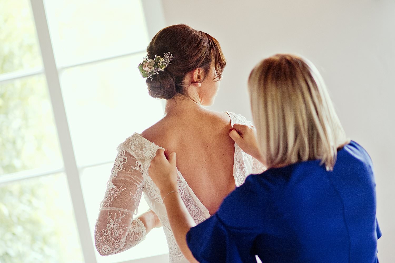 Brautjungfer hilft der Braut ins Kleid