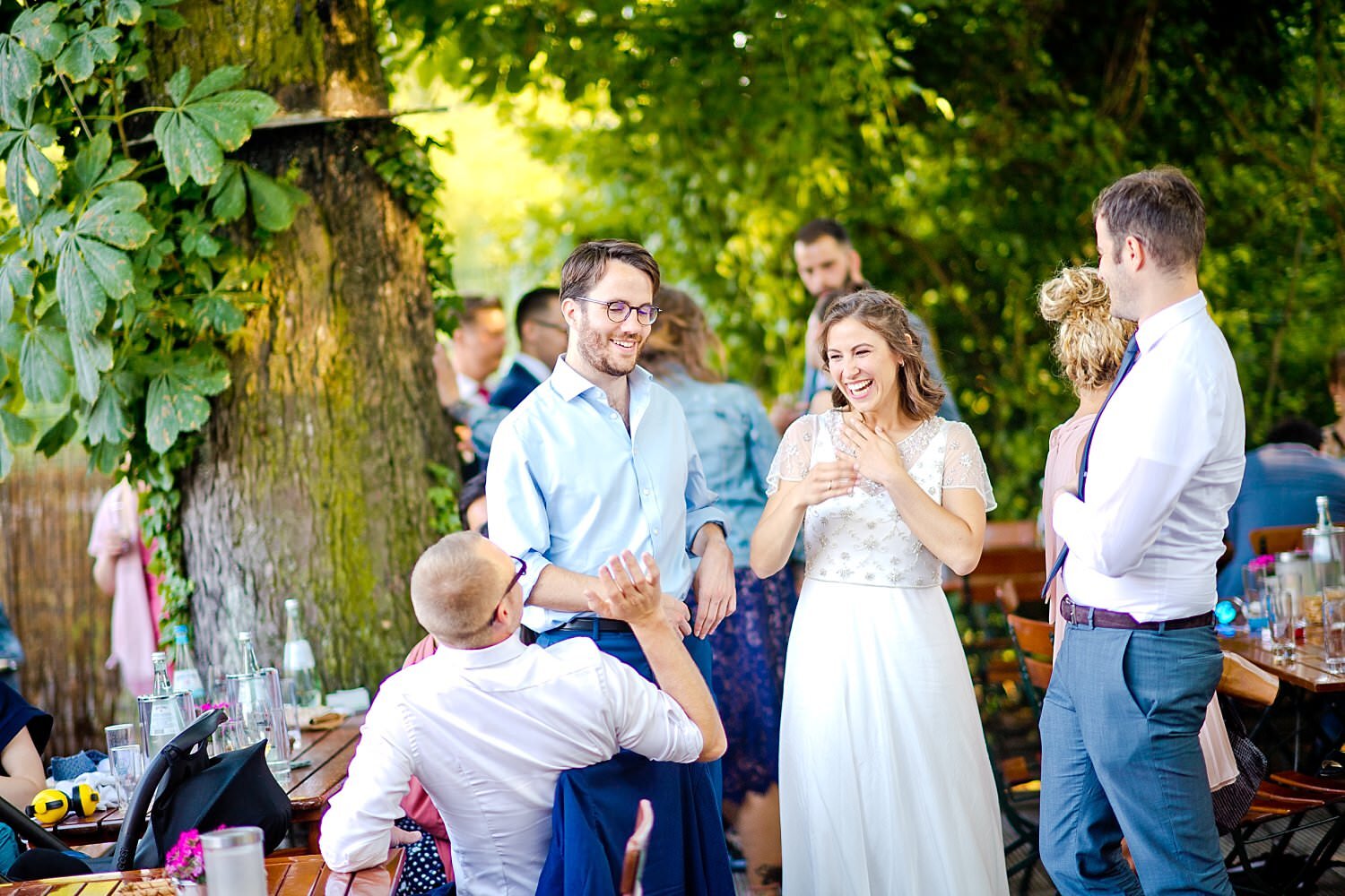 Braut lacht mit Hochzeitsgästen