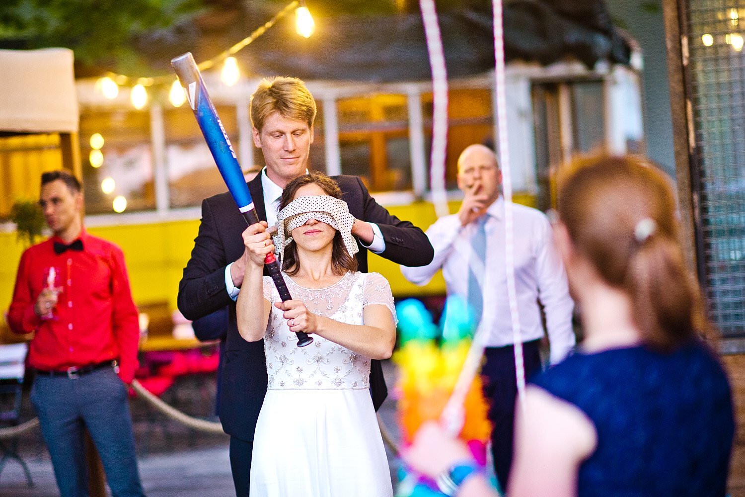 Braut mit Augenbinde hält Baseballschläger beim Hochzeitsspiel